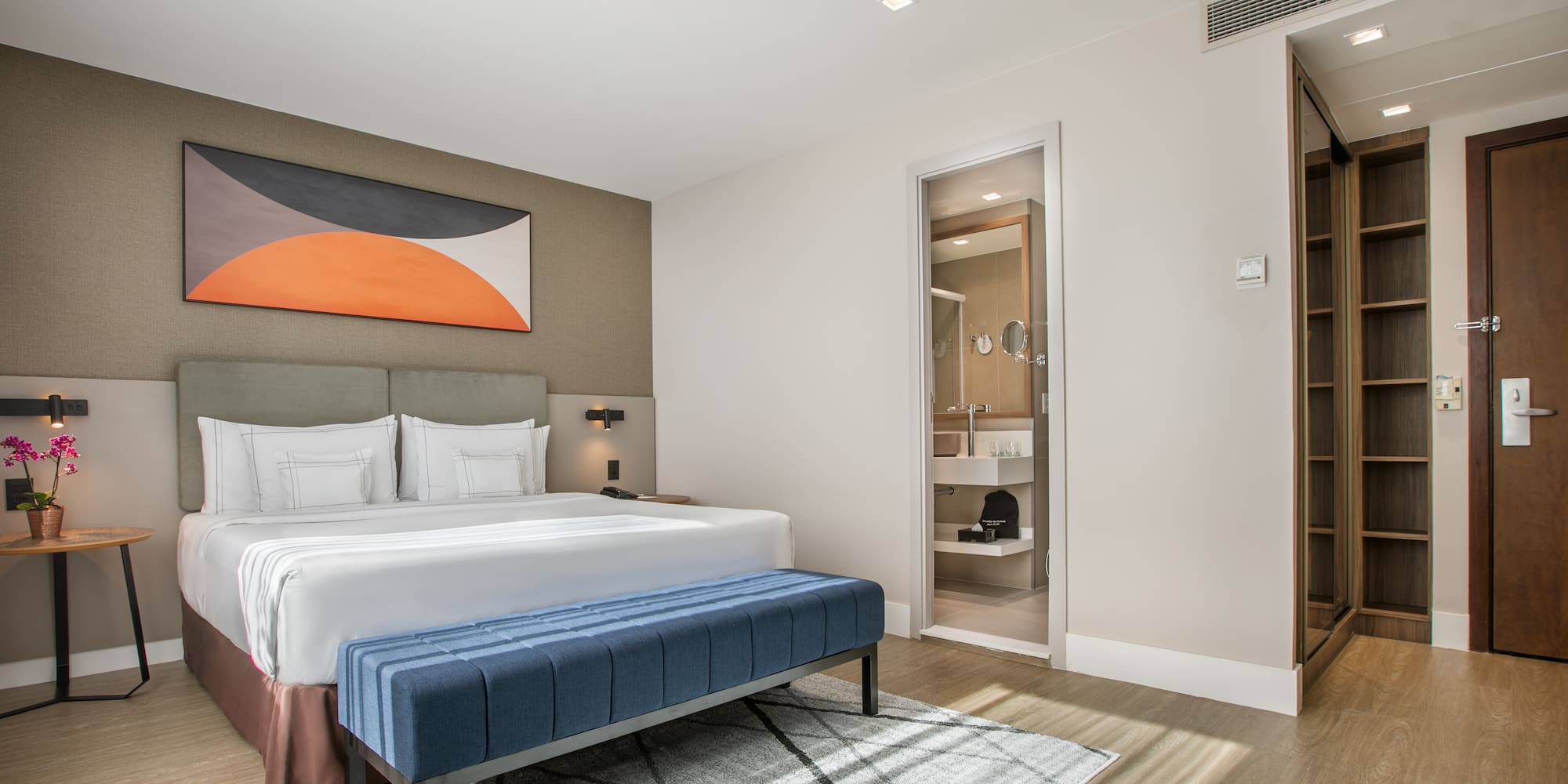 a bedroom with a bed and a blue ottoman