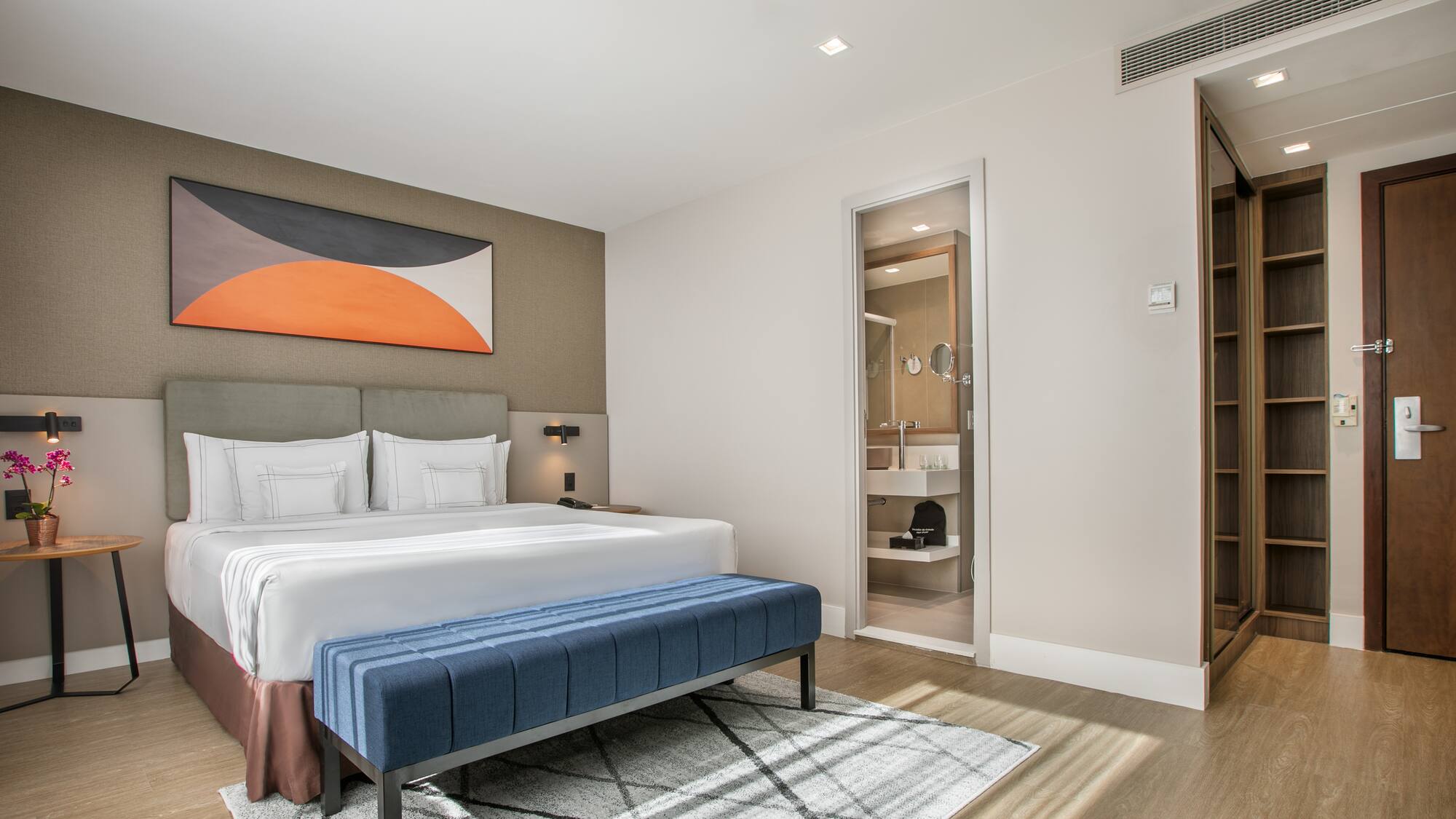 a bedroom with a bed and a blue ottoman