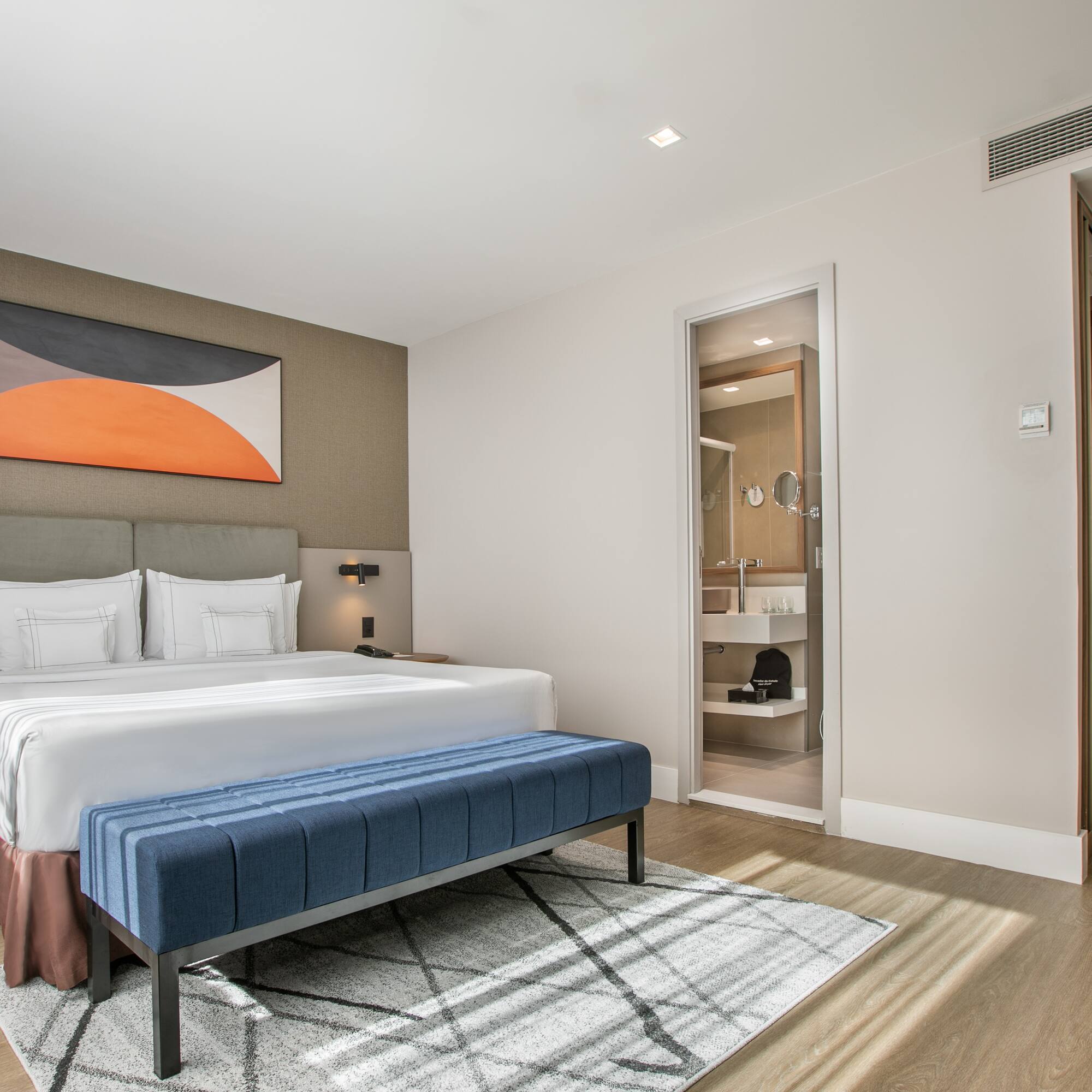 a bedroom with a bed and a blue ottoman