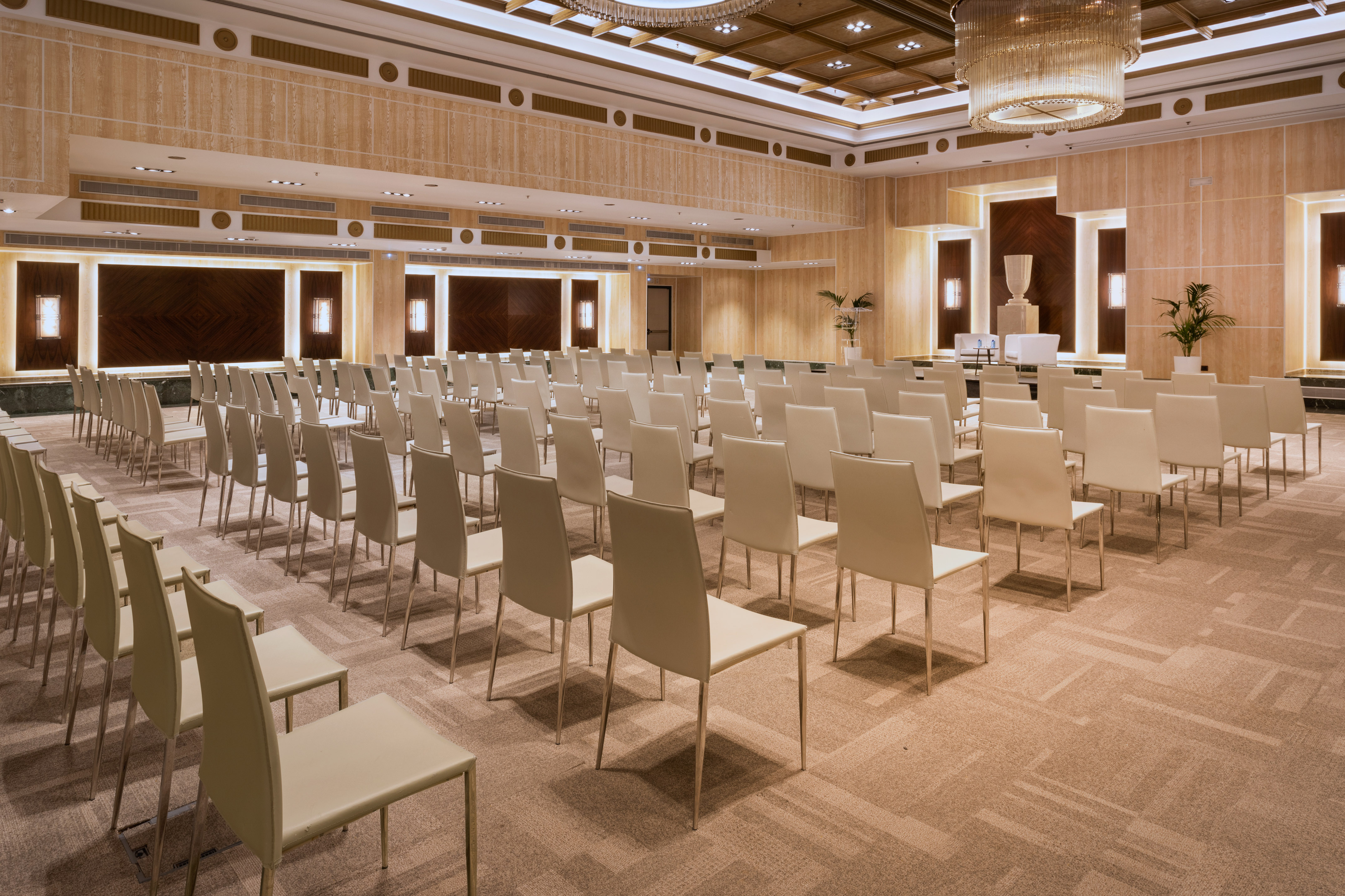 Elegant empty conference hall with rows of chairs and a stage setup.