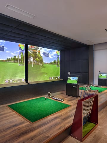 a room with a golf course and a large screen