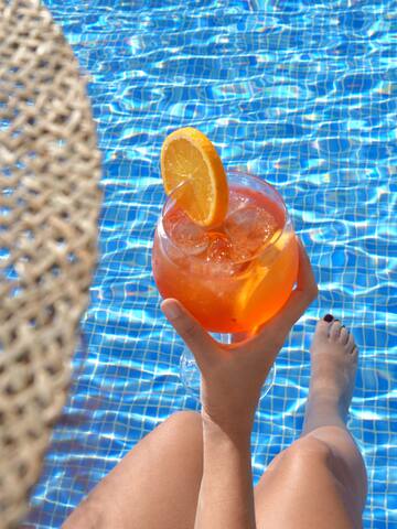a person holding a drink in front of a pool
