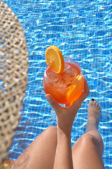 a person holding a drink in front of a pool
