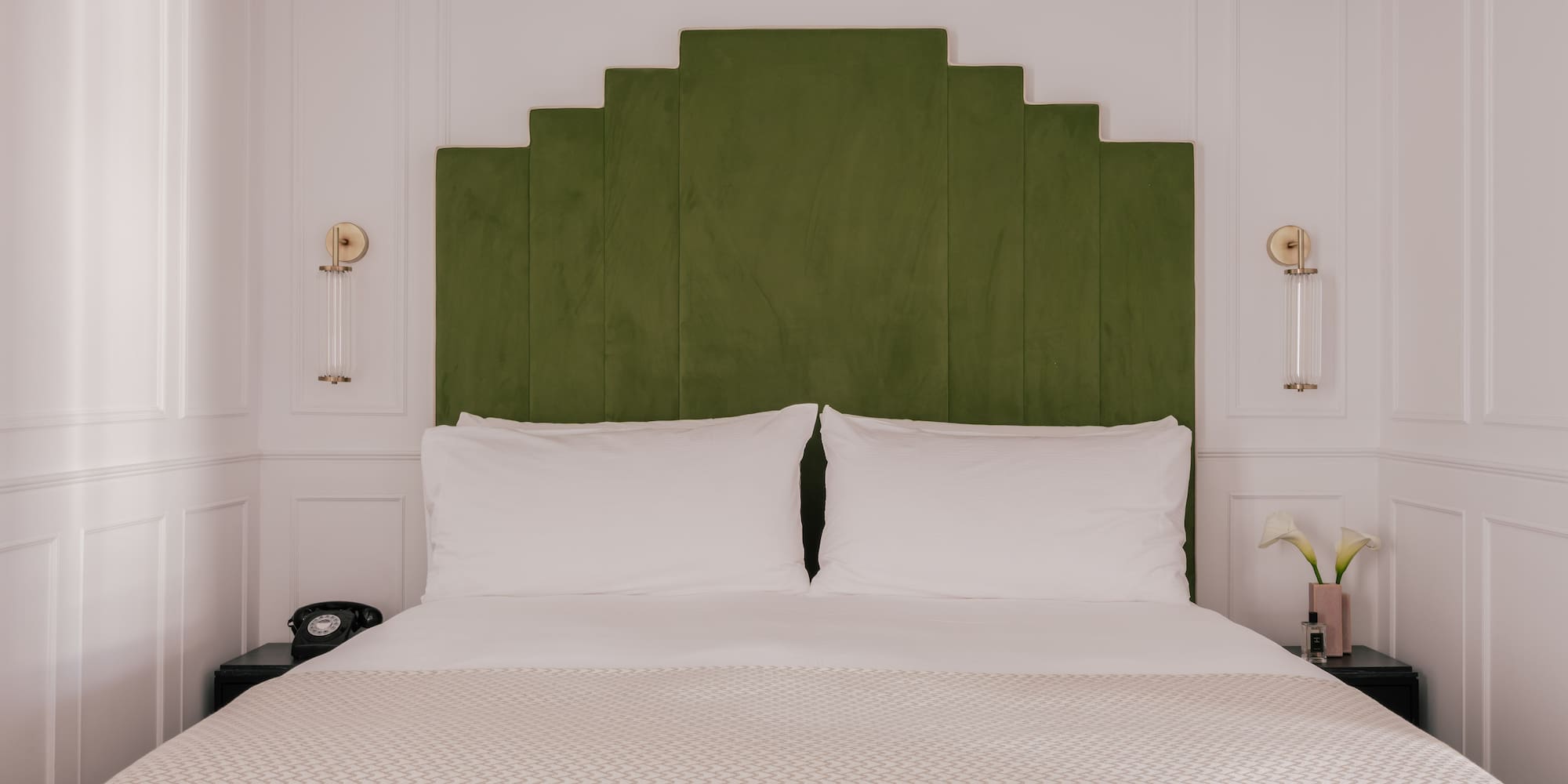Modern boutique hotel bedroom with green velvet headboard.