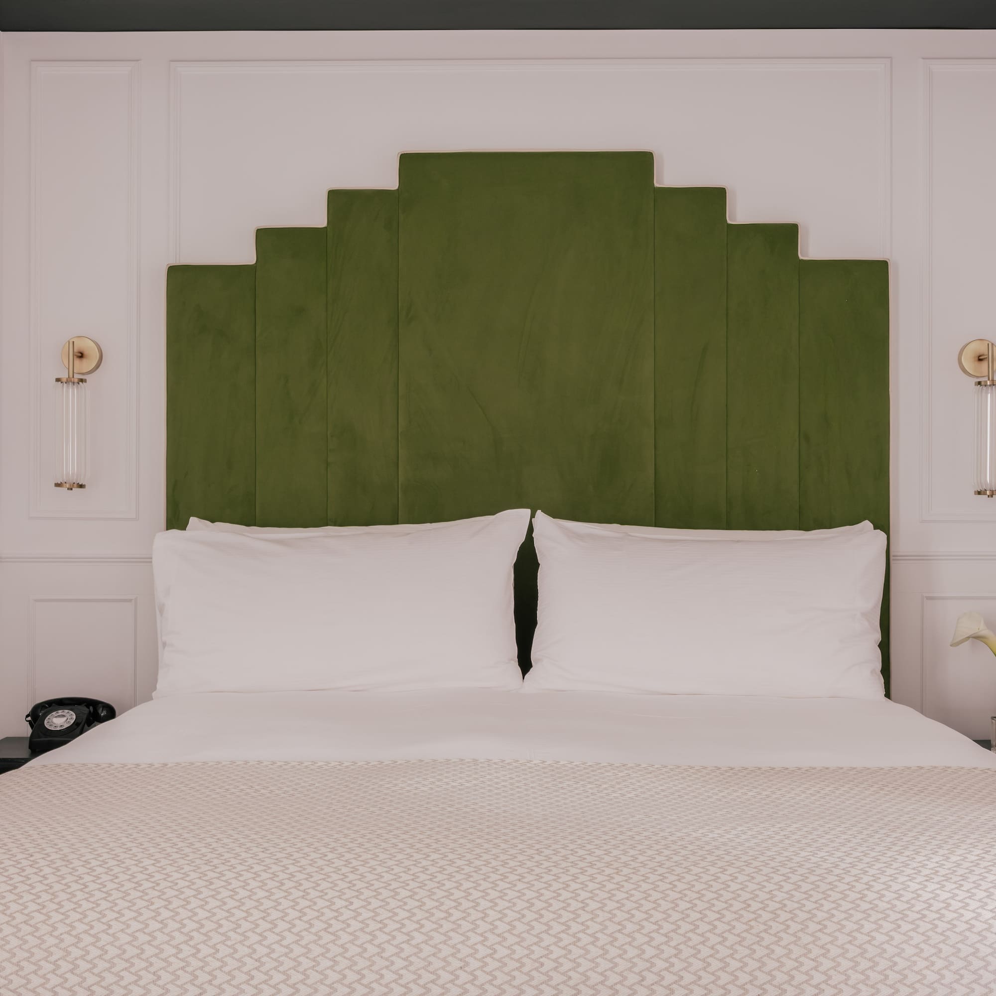 Modern boutique hotel bedroom with green velvet headboard.