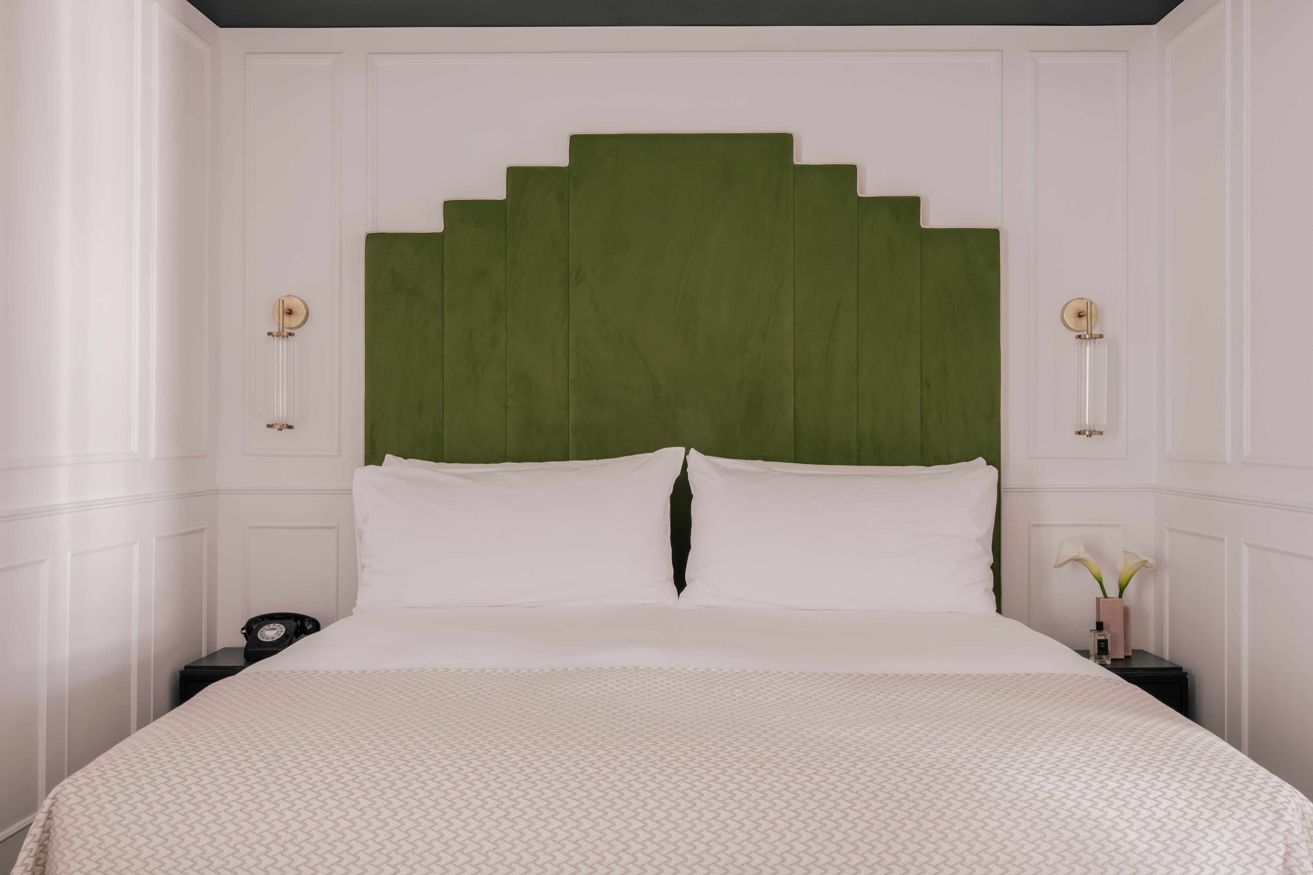 Modern boutique hotel bedroom with green velvet headboard.