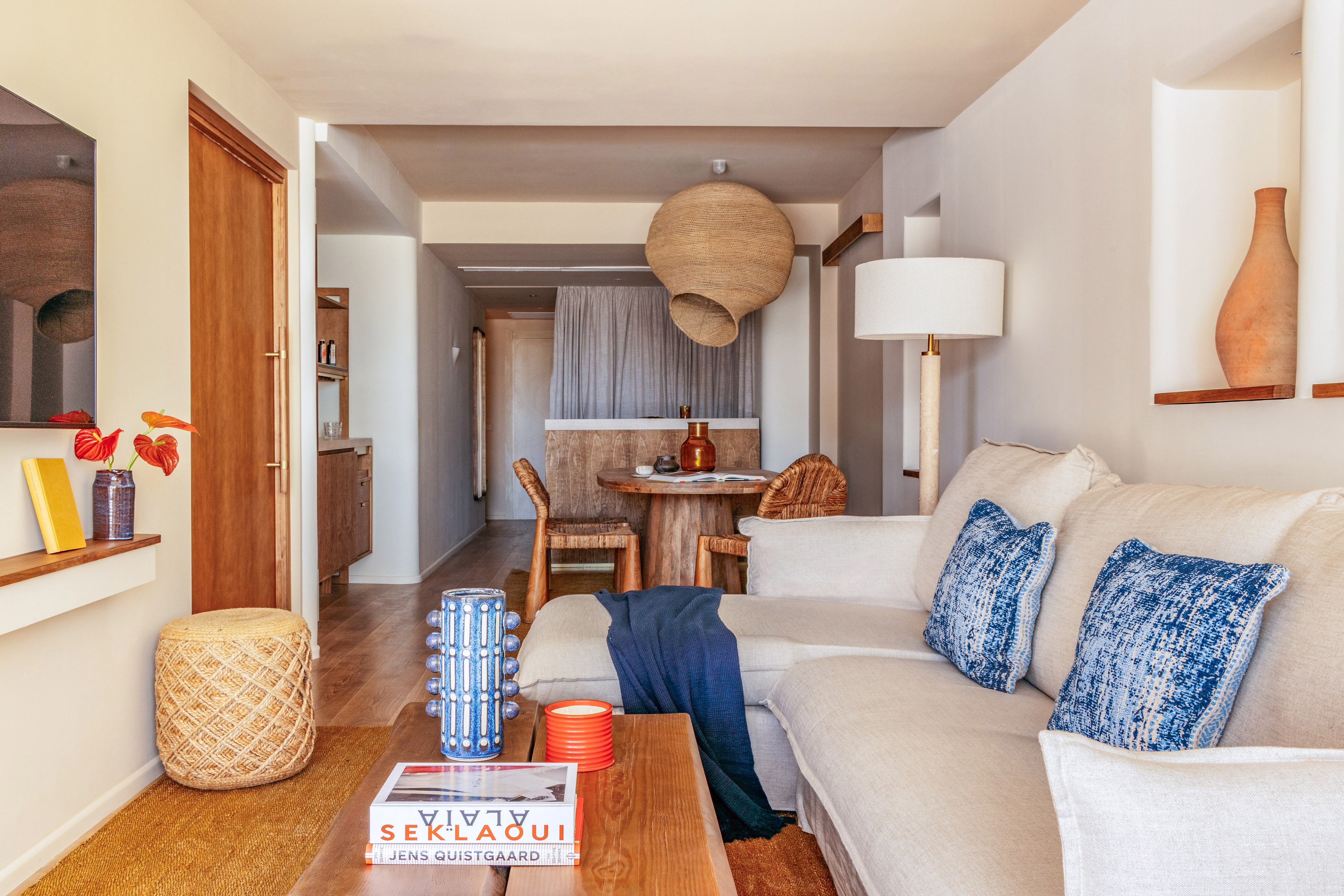 Modern boho living room: neutral sofa, natural wood, woven lamp, blue accents.