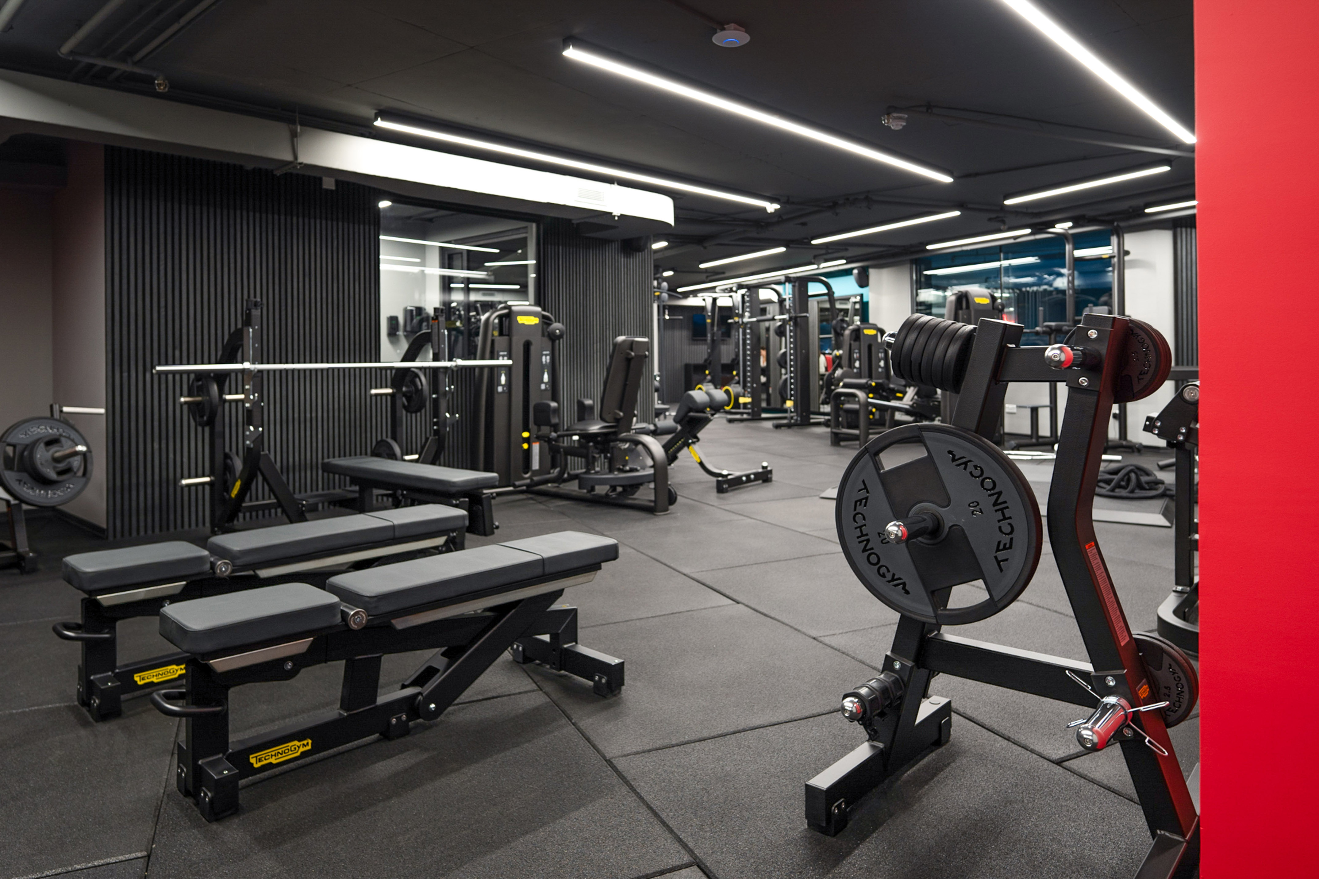 Modern gym with Technogym weightlifting equipment, exercise benches, and machines.