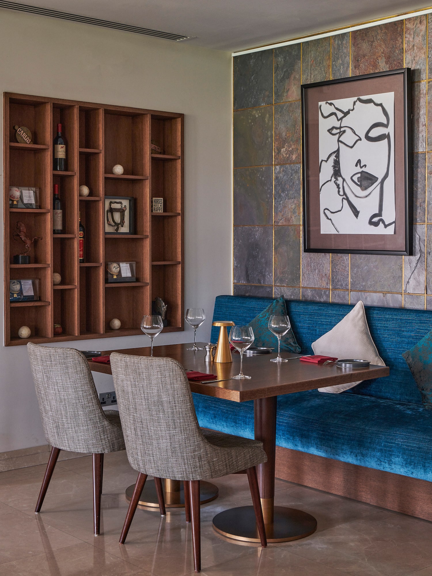 a table with wine glasses and a blue couch in a room with a painting on the wall
