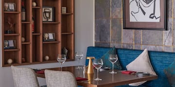 a table with wine glasses and a blue couch in a room with a painting on the wall