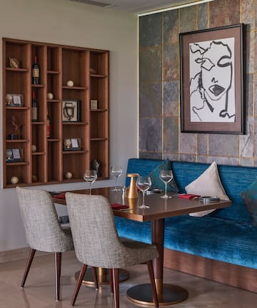 a table with wine glasses and a blue couch in a room with a painting on the wall