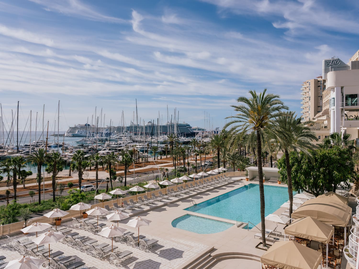 a pool and palm trees with boats in the background