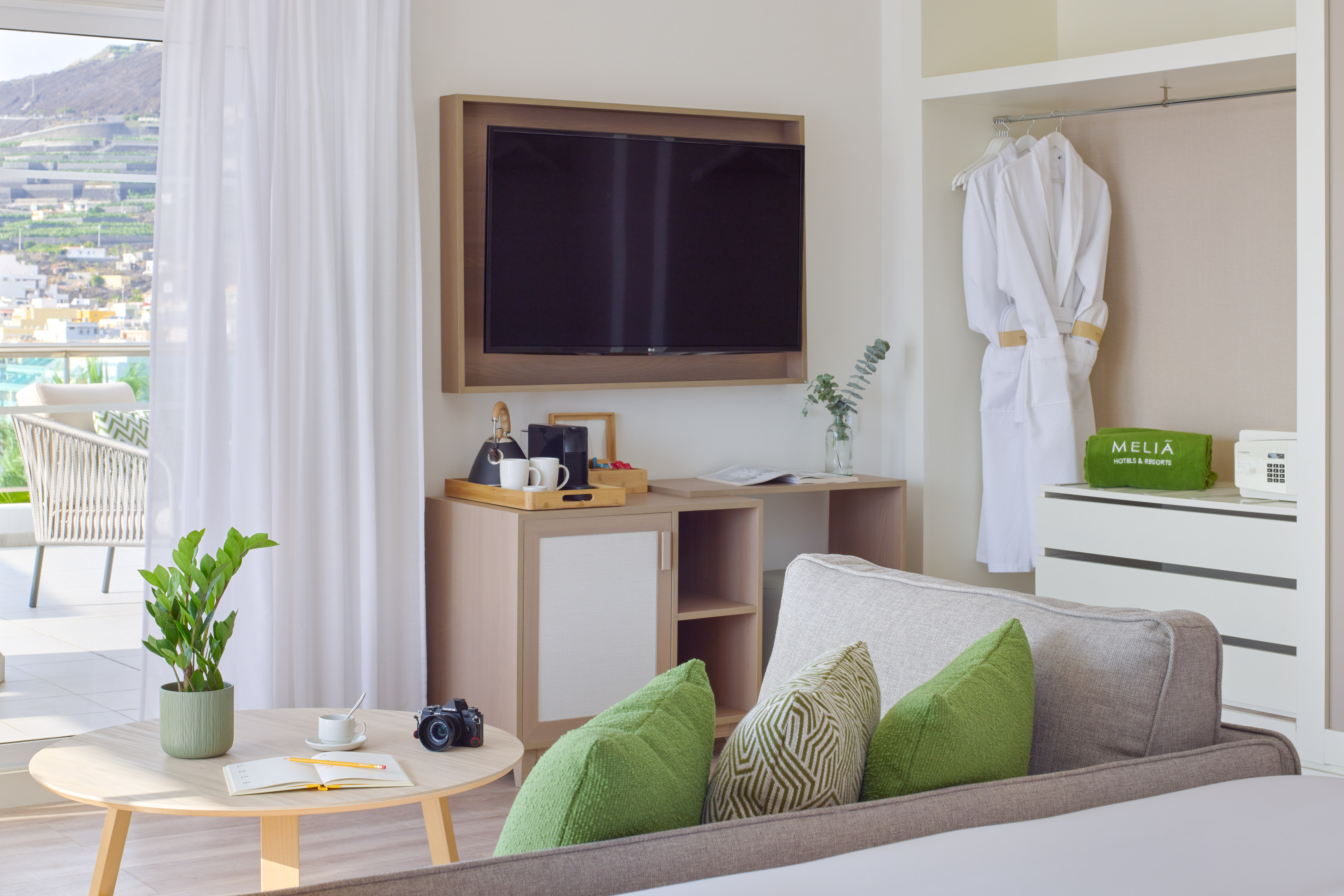 Melia hotel room with balcony, flat-screen TV, sofa, and mountain view.
