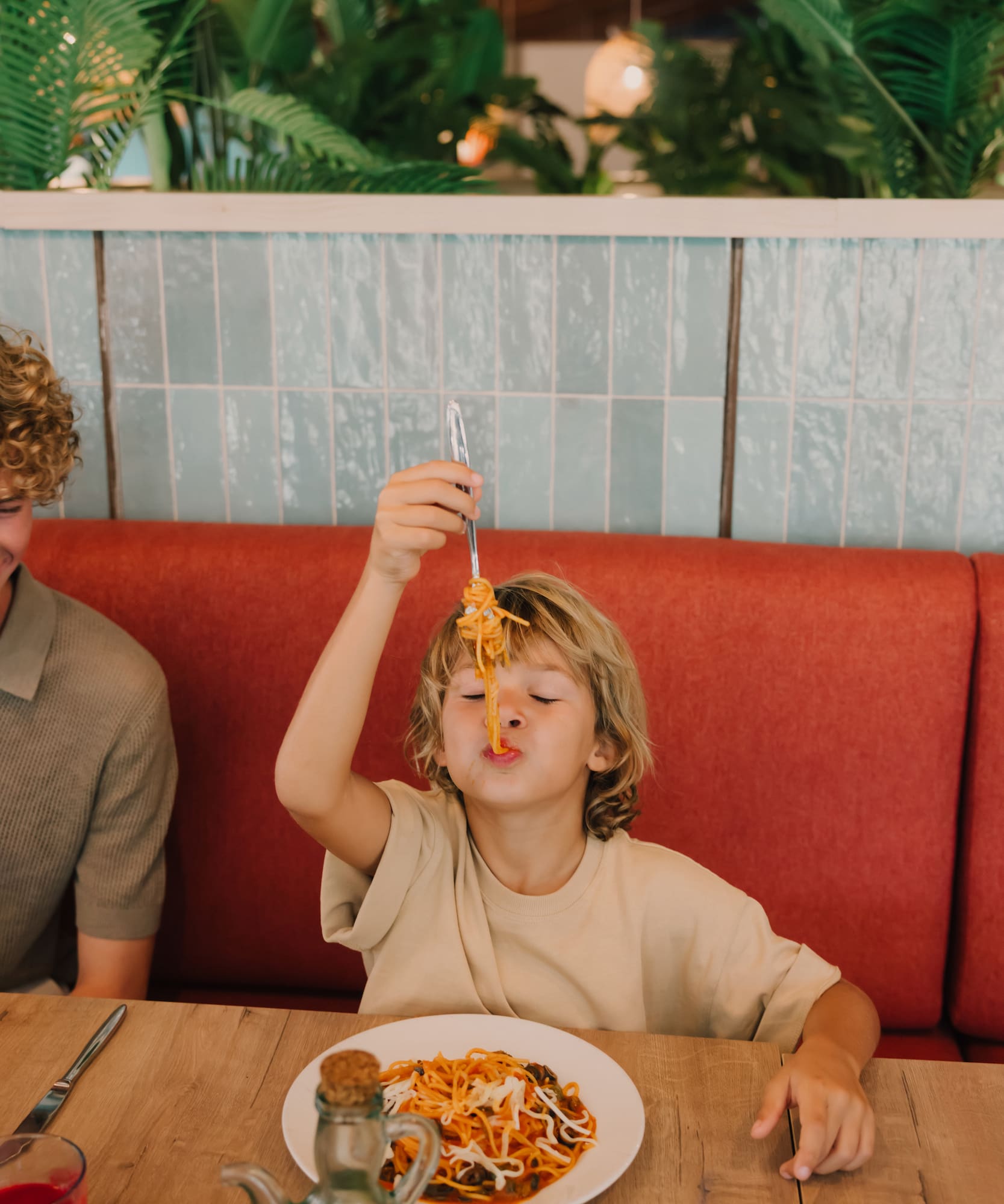 a boy holding a fork over his face while eating spaghetti