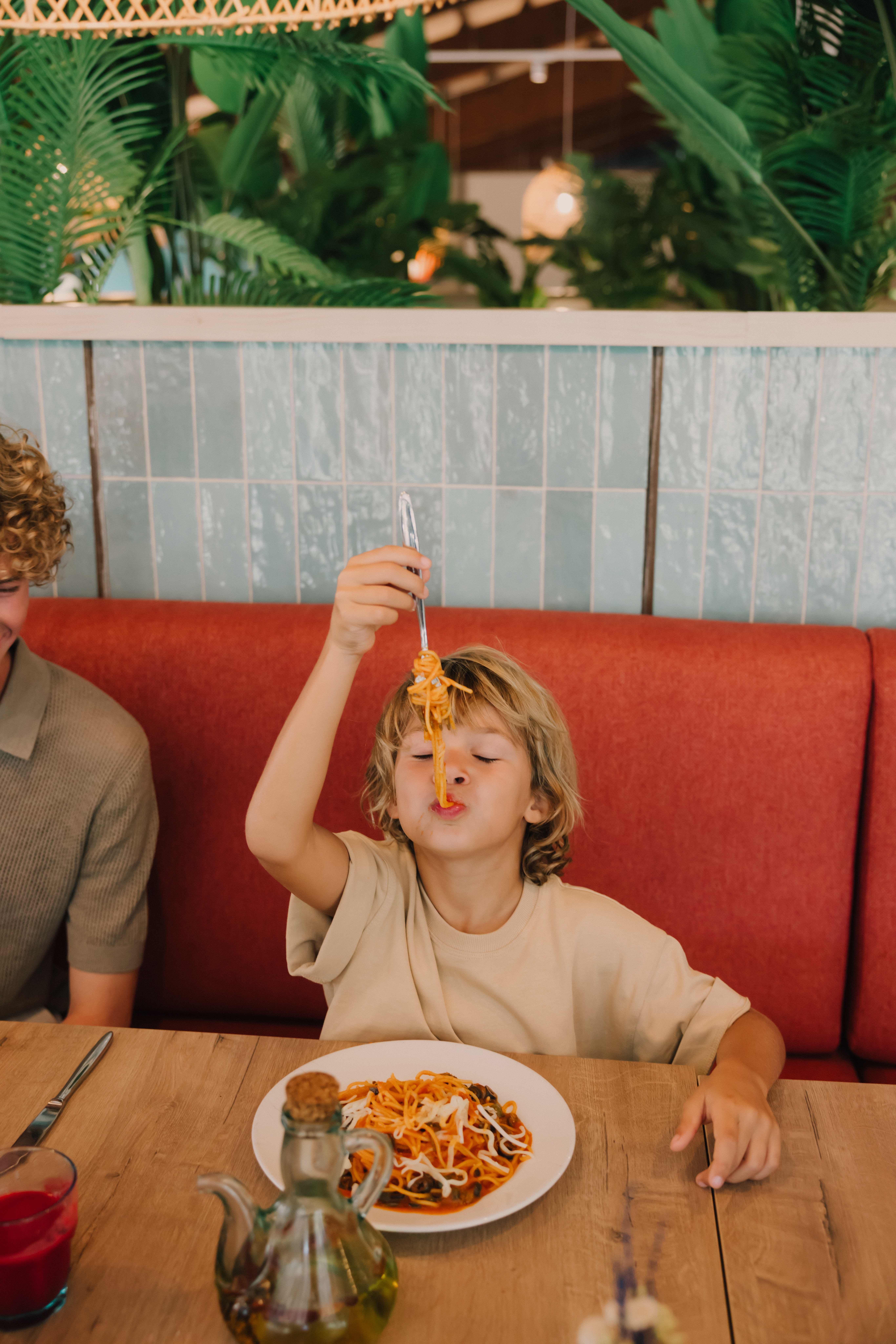 a boy holding a fork over his face while eating spaghetti