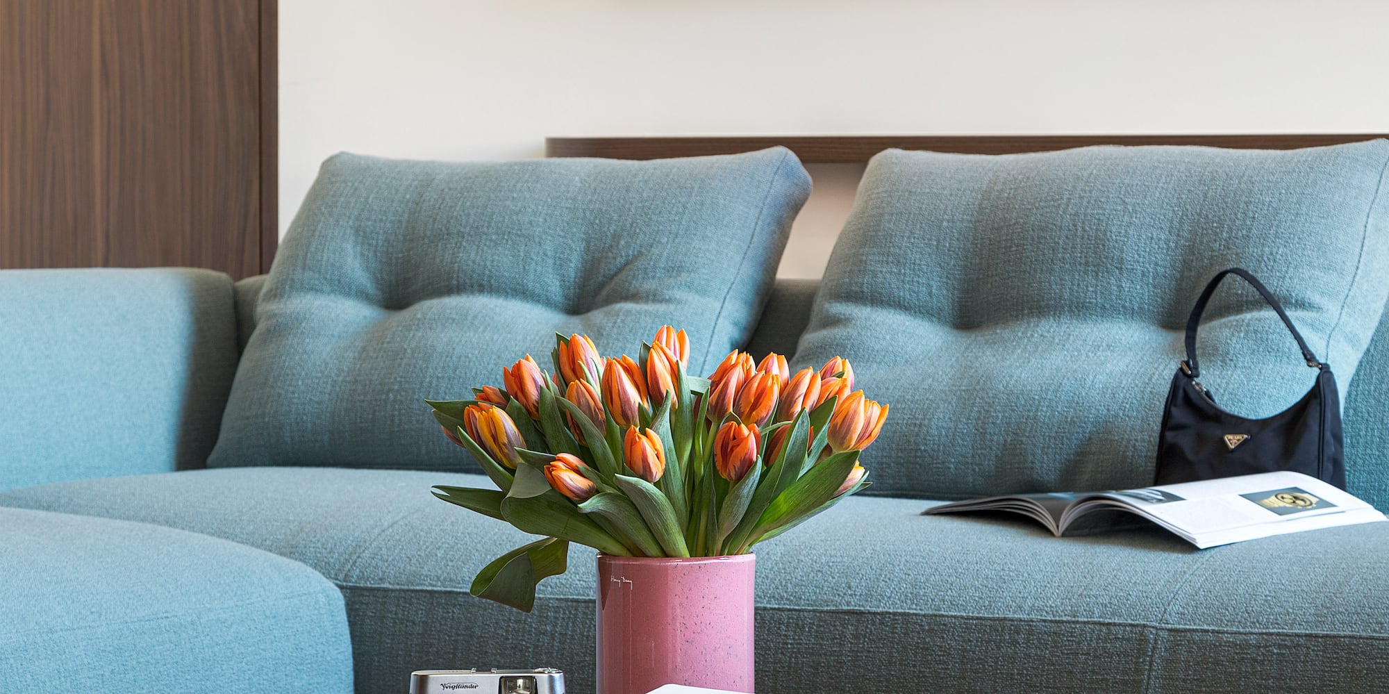 a couch with a vase of flowers and a camera