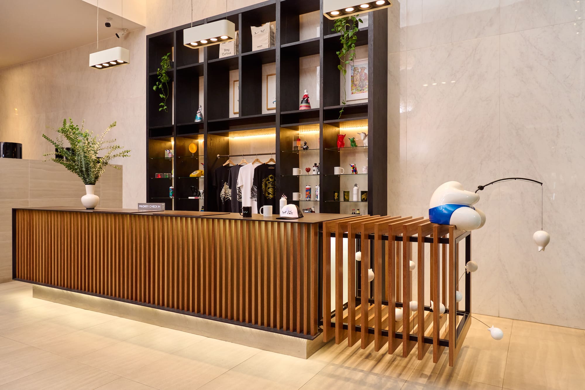 Contemporary hotel reception desk, wood slats, retail display, fishing sculpture.