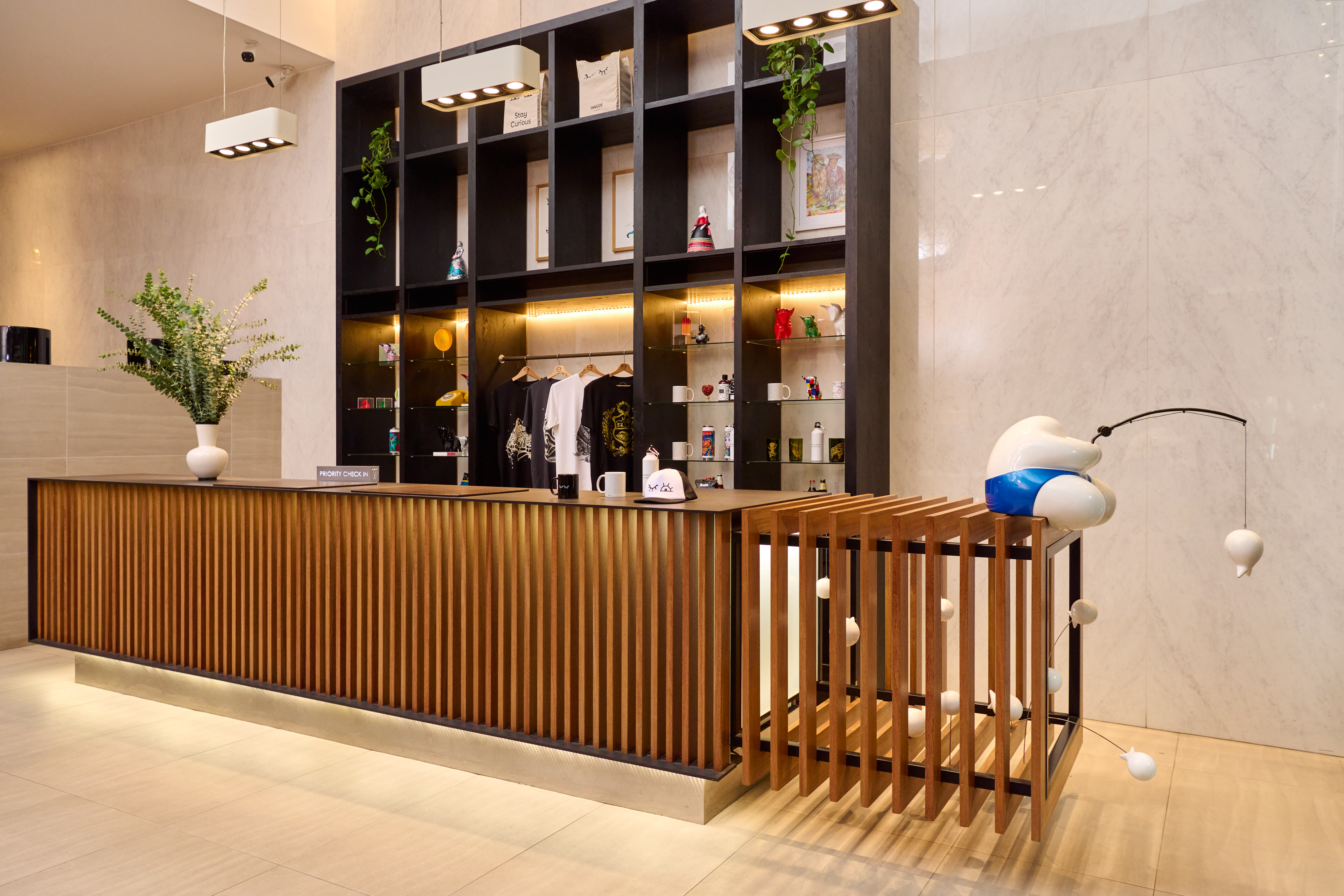 Contemporary hotel reception desk, wood slats, retail display, fishing sculpture.