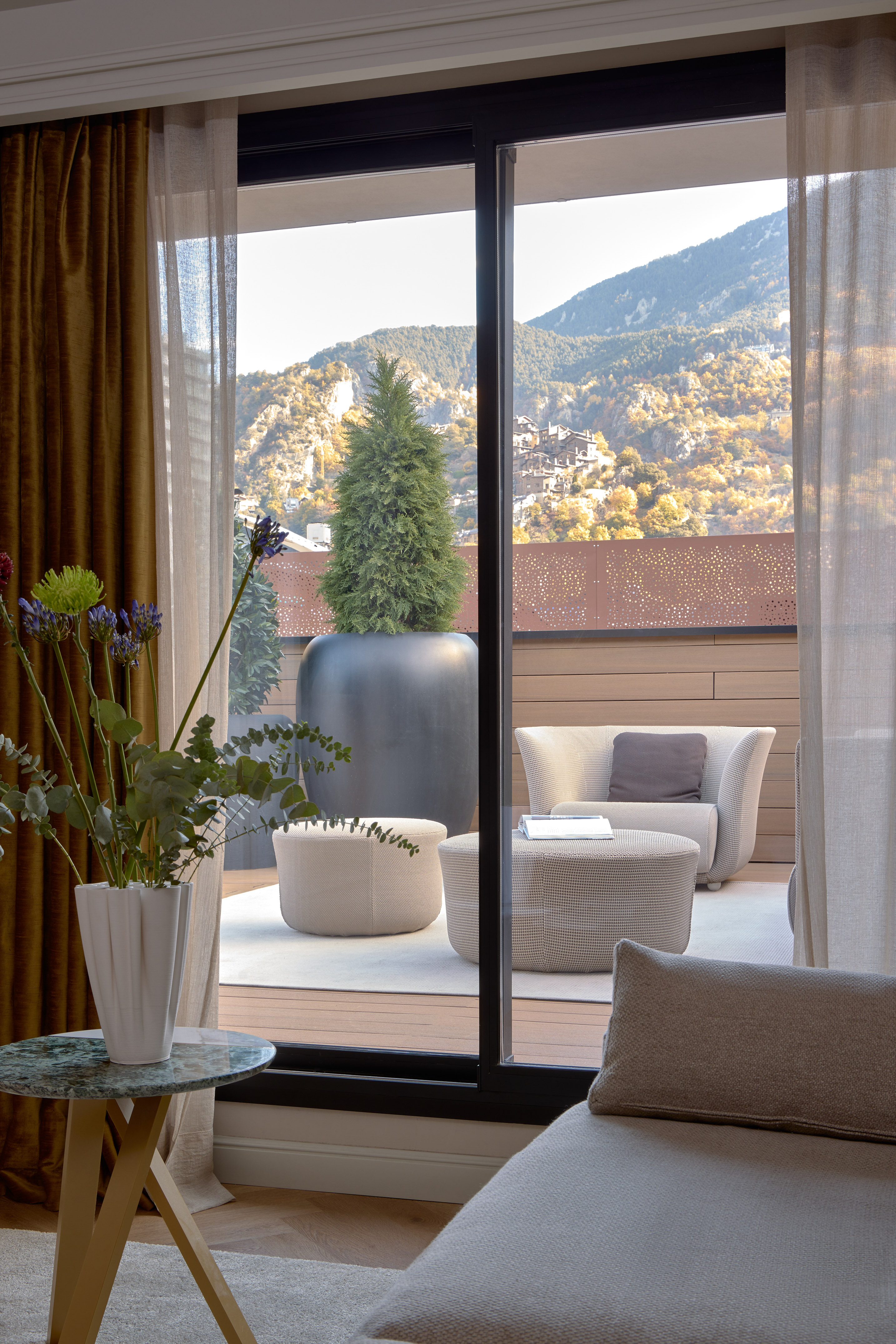 Modern balcony with outdoor seating and scenic mountain village view.