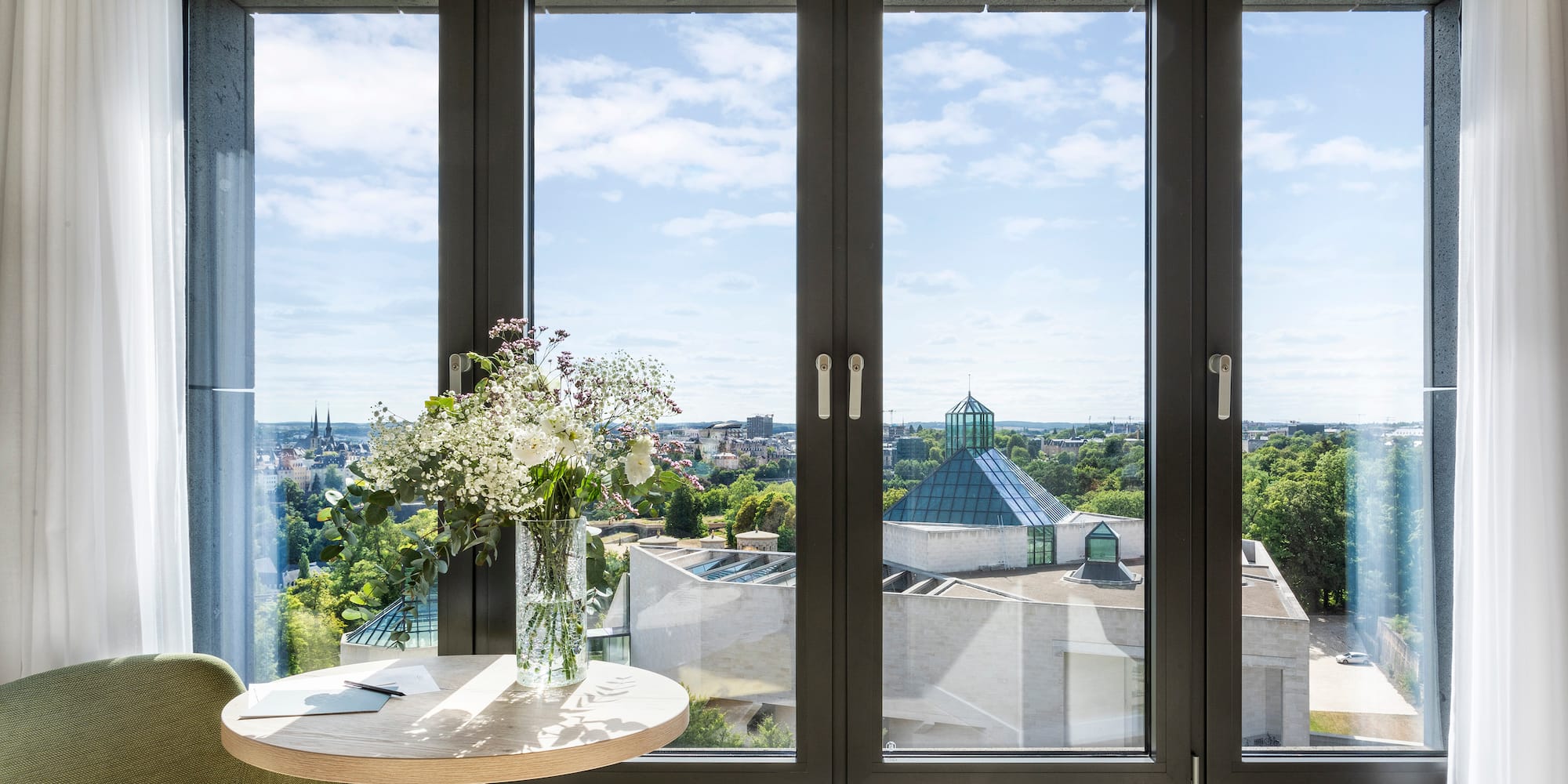 a window with a vase of flowers and a city view
