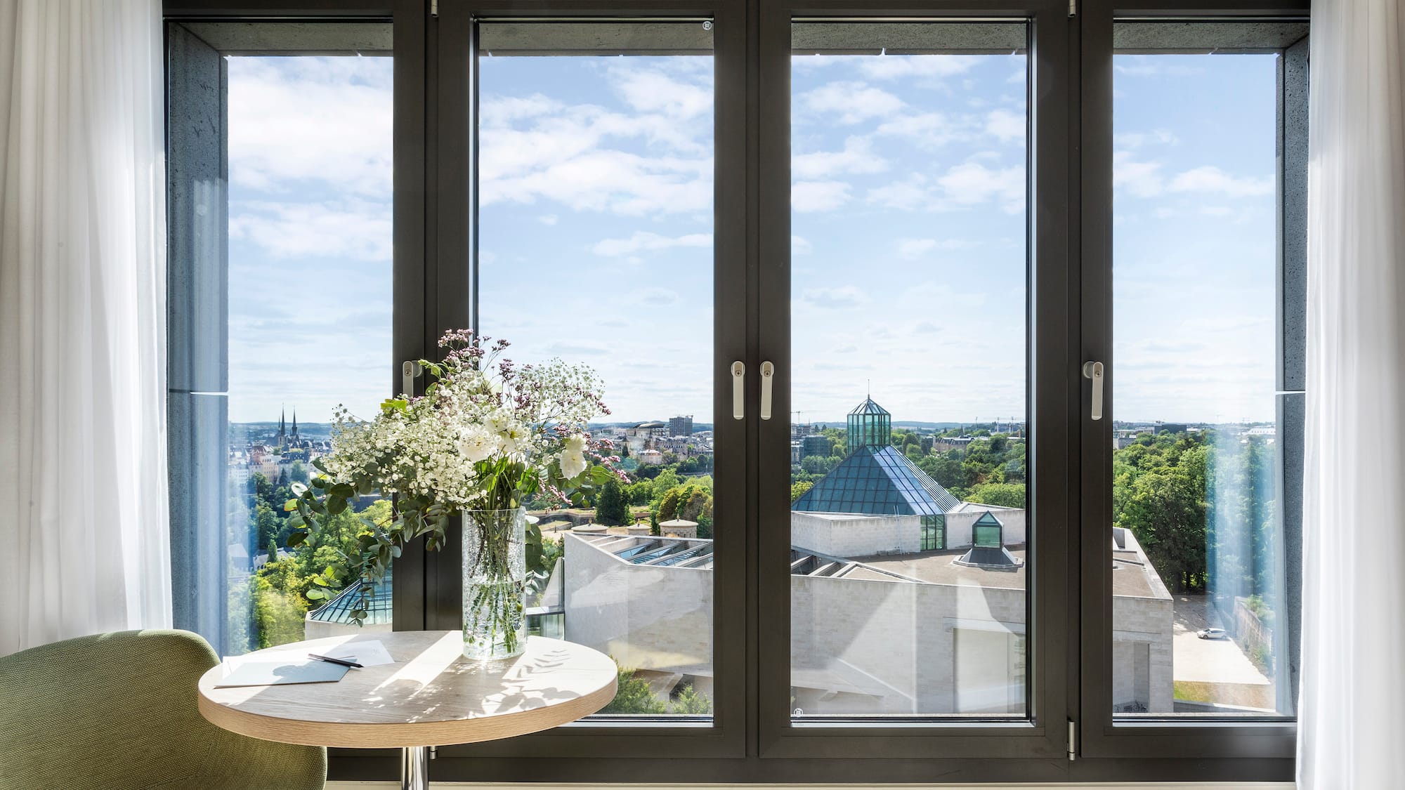 a window with a vase of flowers and a city view