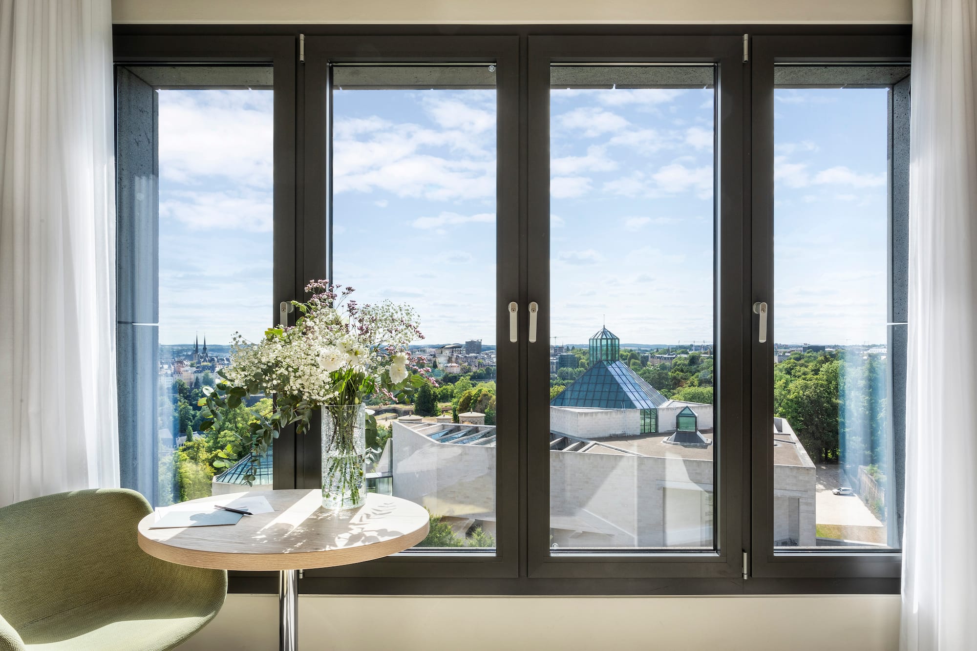 a window with a vase of flowers and a city view