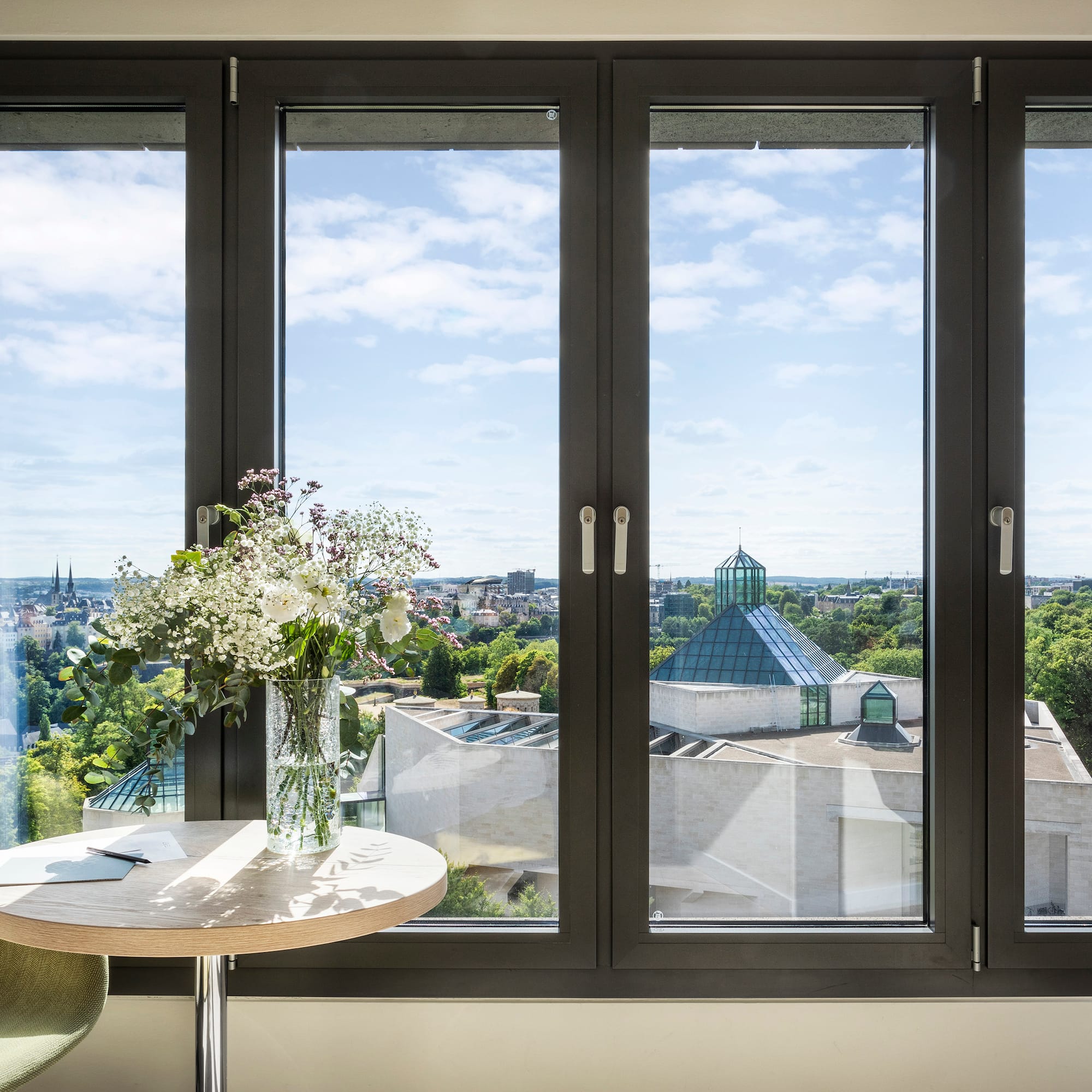 a window with a vase of flowers and a city view