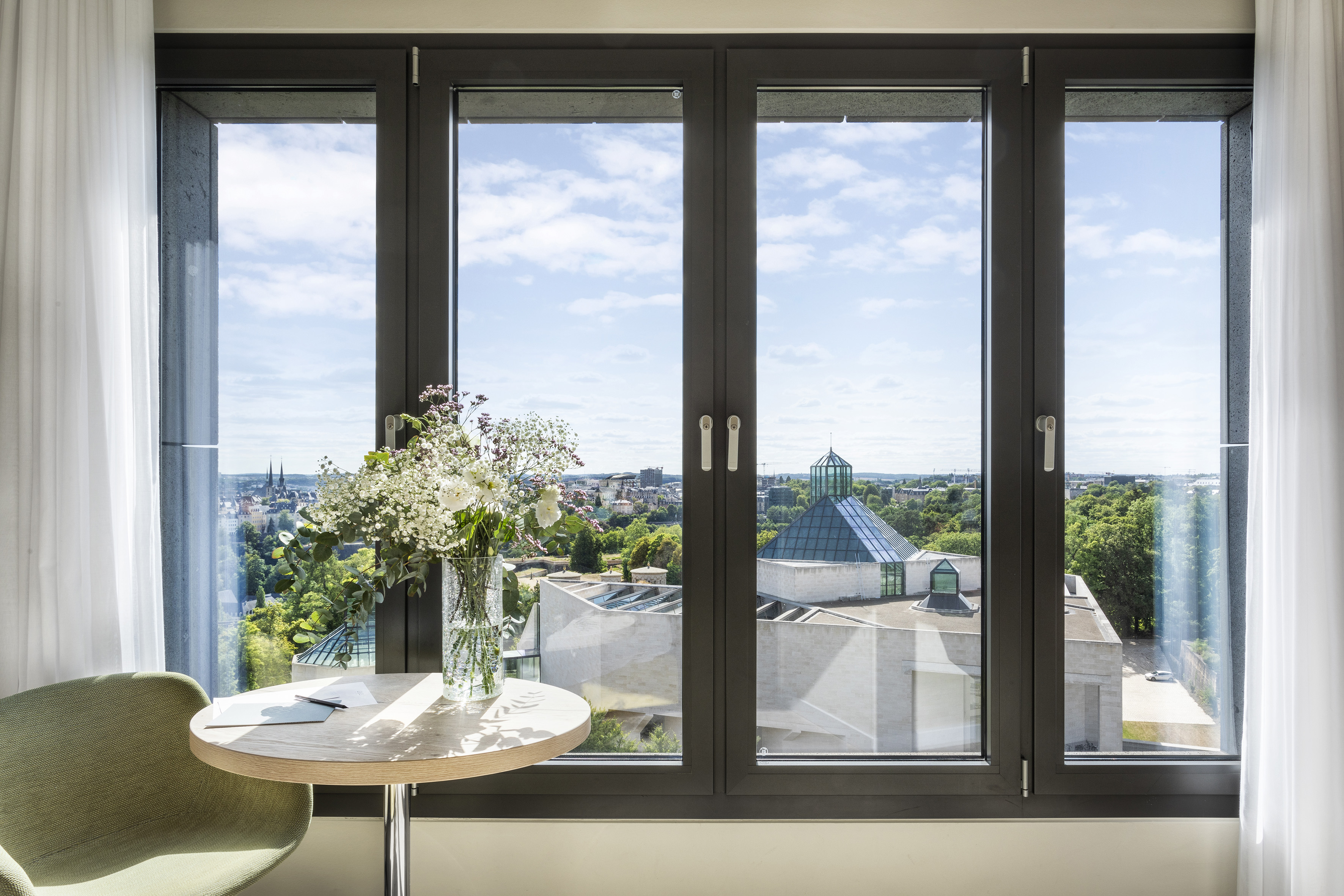 a window with a vase of flowers and a city view