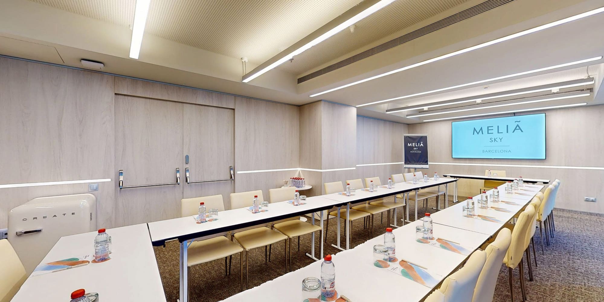Meliá Sky Barcelona meeting room with modern tables, chairs, and large screen.