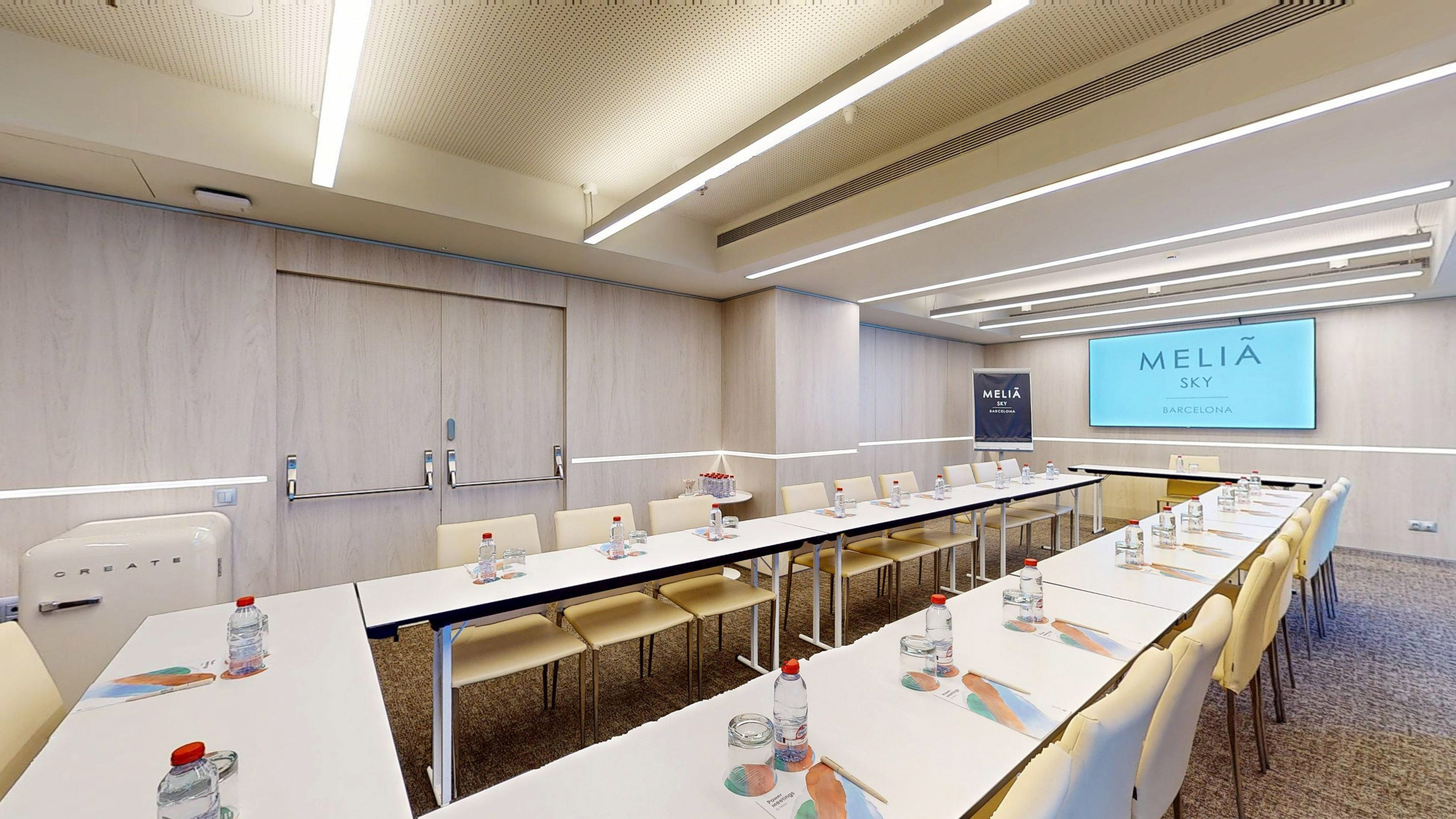 Meliá Sky Barcelona meeting room with modern tables, chairs, and large screen.