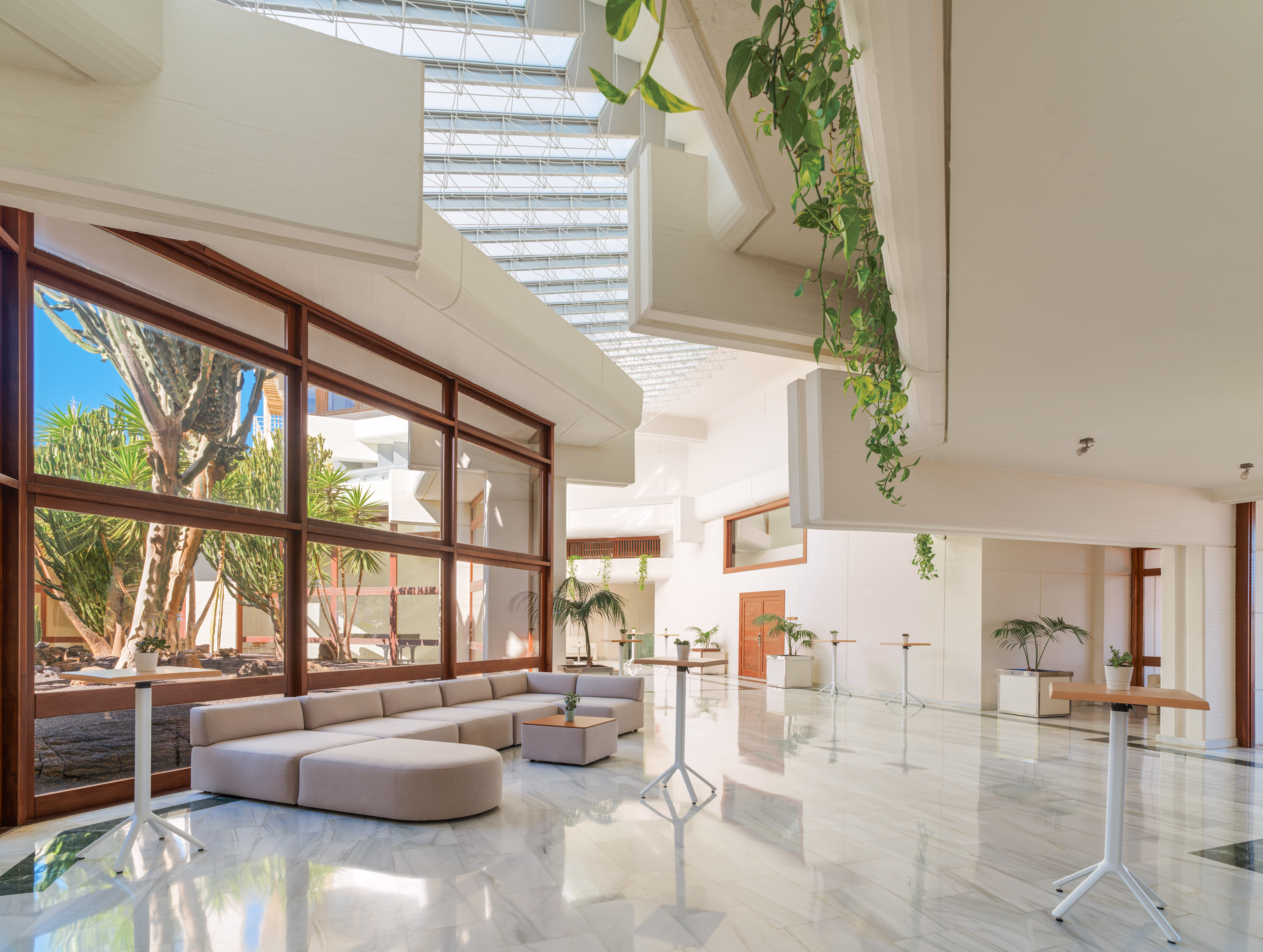 Bright, modern hotel lobby with marble floor, large windows, and skylight.
