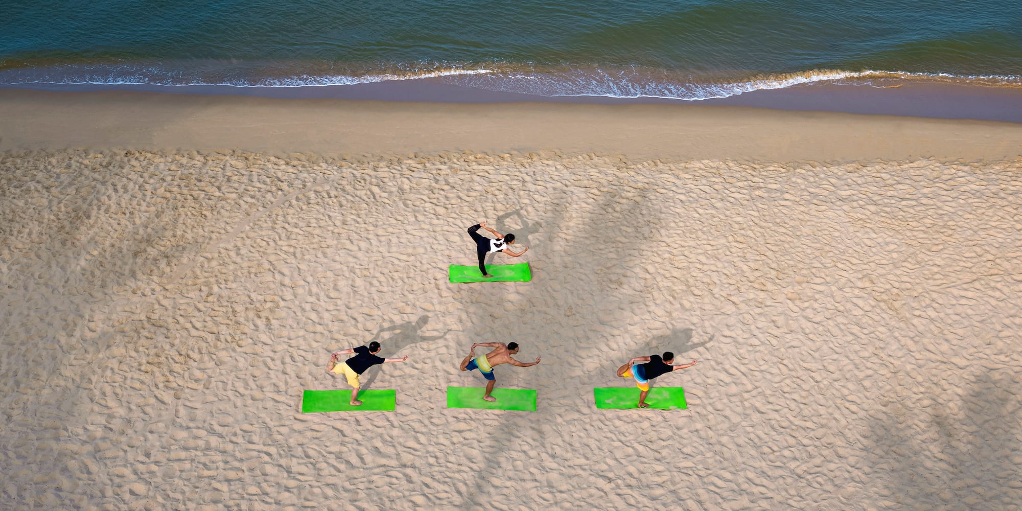 a group of people doing yoga on the beach