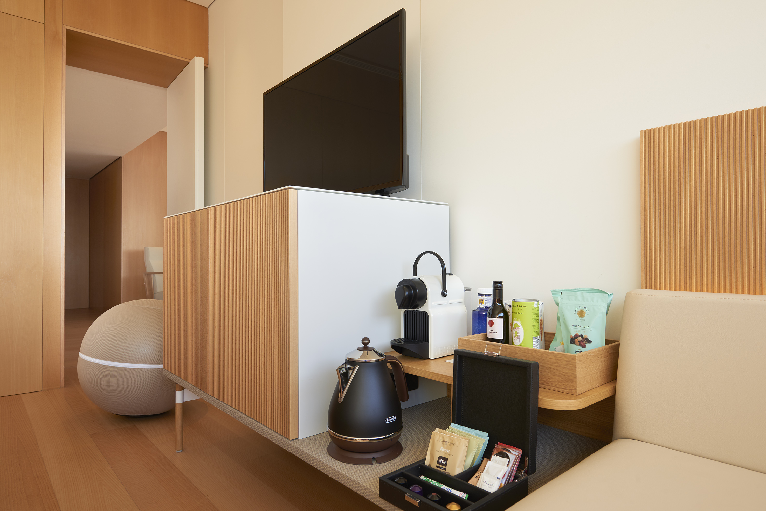 Modern hotel room with TV, coffee station, kettle, and minibar snacks.