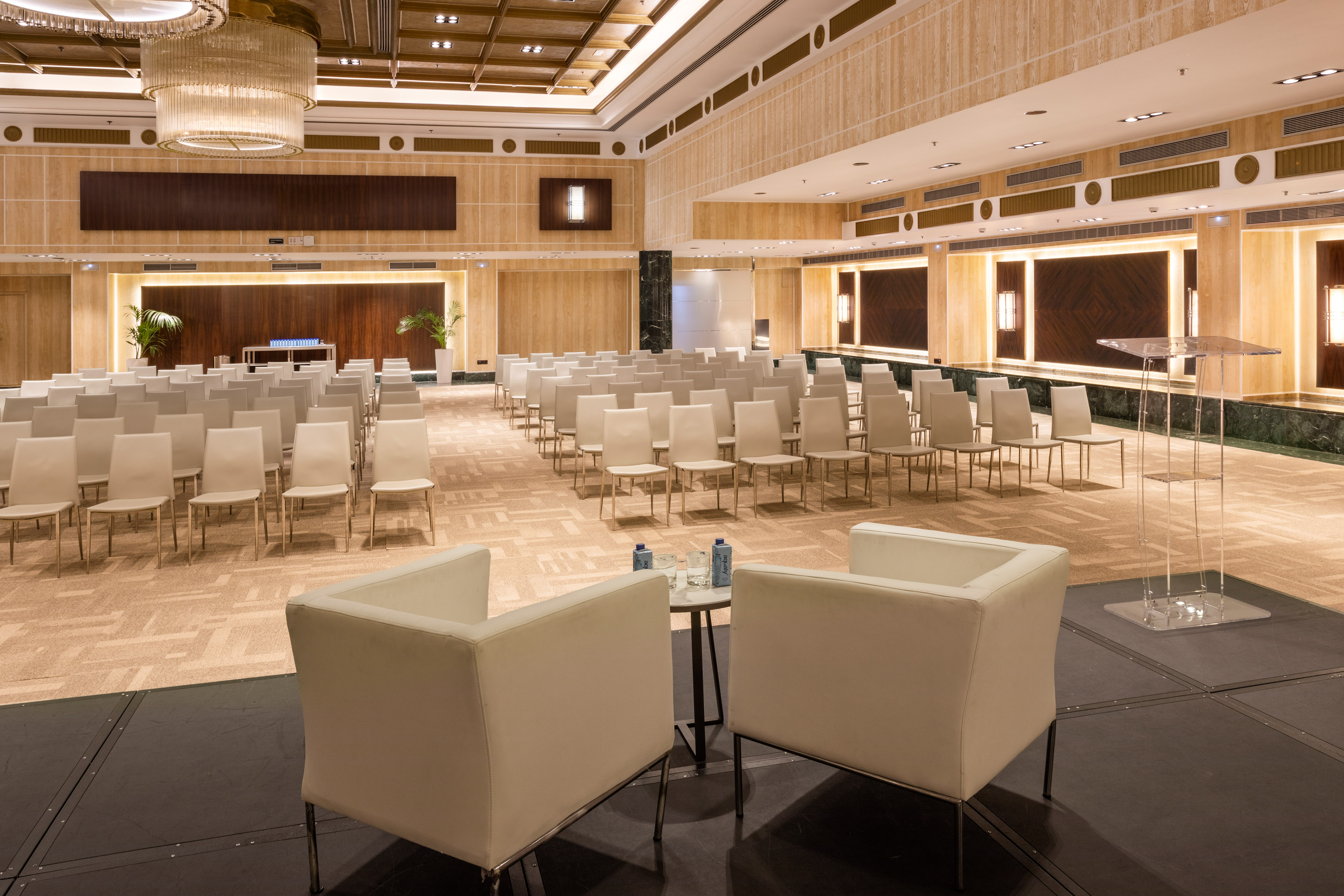 Empty modern conference room with white chairs, stage, and podium.
