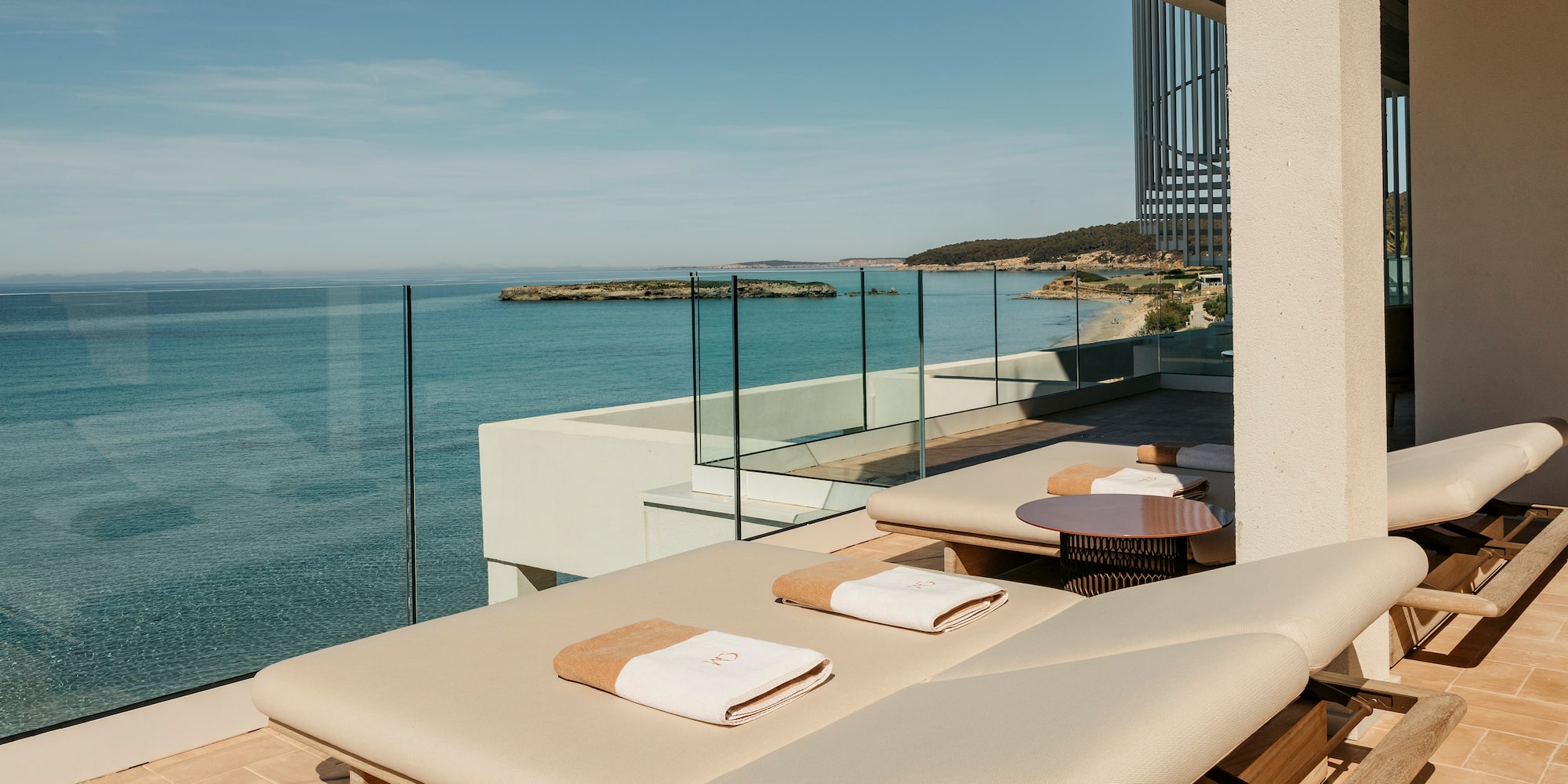 a deck with chairs and a glass railing overlooking the ocean