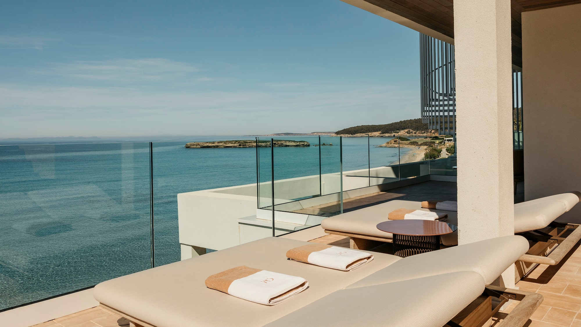 a deck with chairs and a glass railing overlooking the ocean