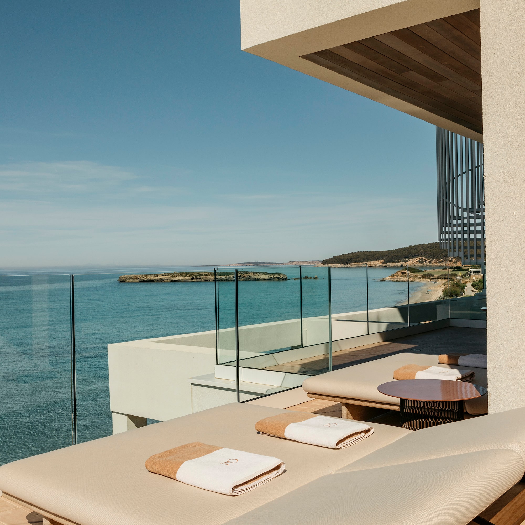 a deck with chairs and a glass railing overlooking the ocean