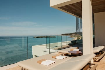 a deck with chairs and a glass railing overlooking the ocean