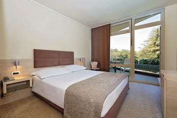 a bed with a brown headboard and a chair in a room with glass doors
