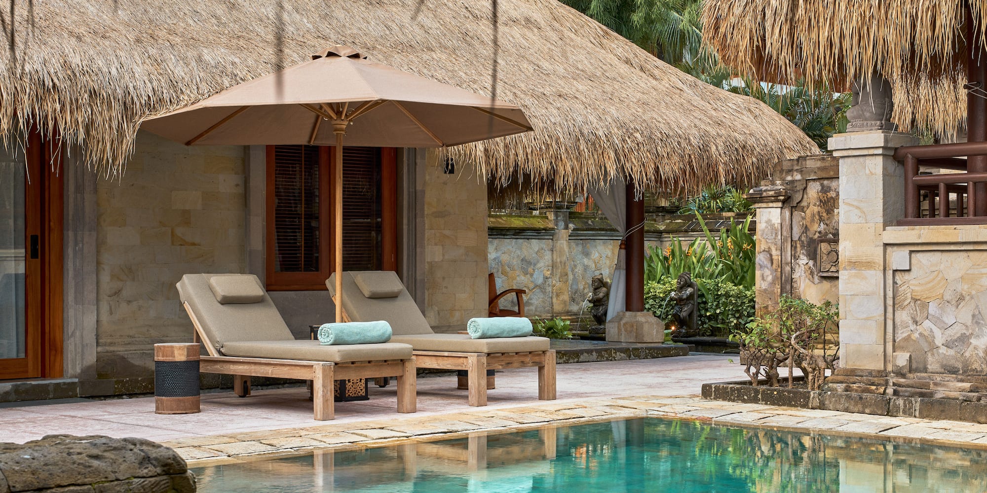 a pool with lounge chairs and umbrella by a building