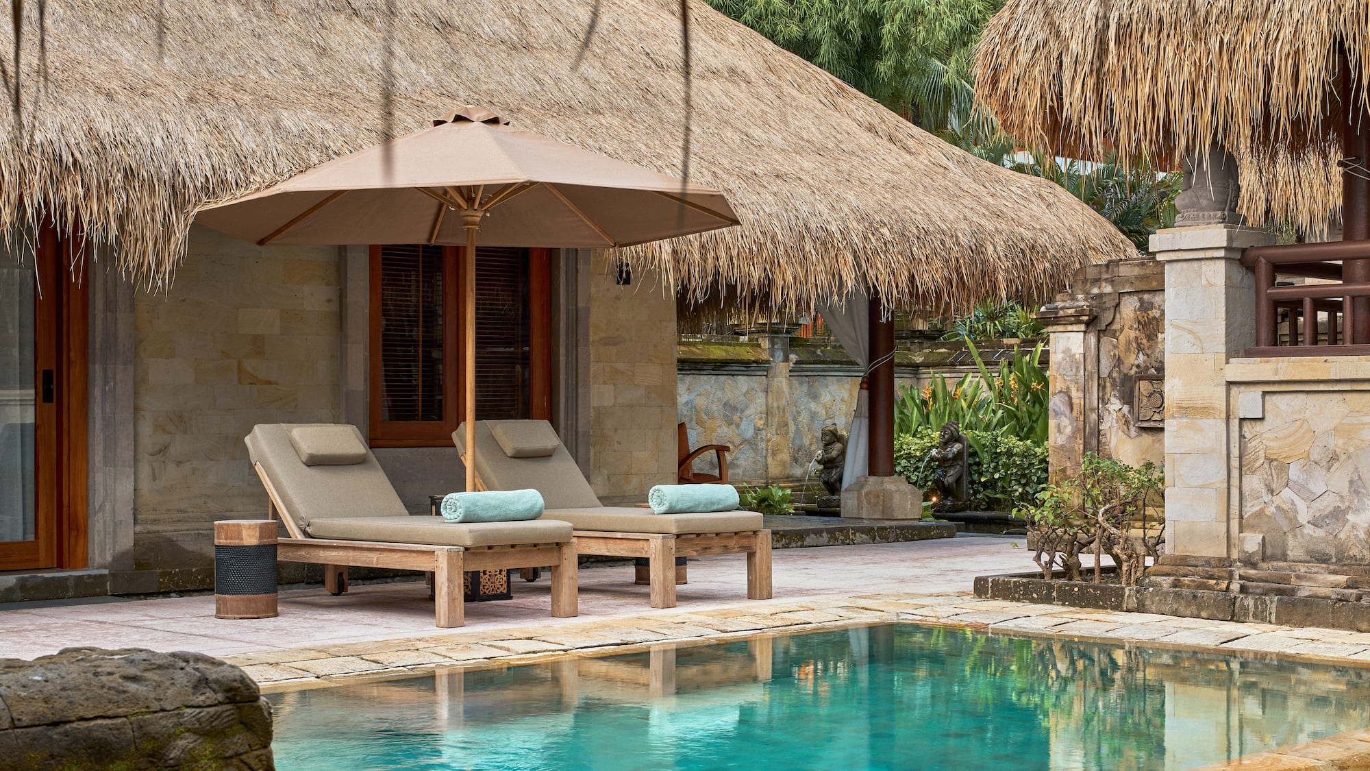 a pool with lounge chairs and umbrella by a building