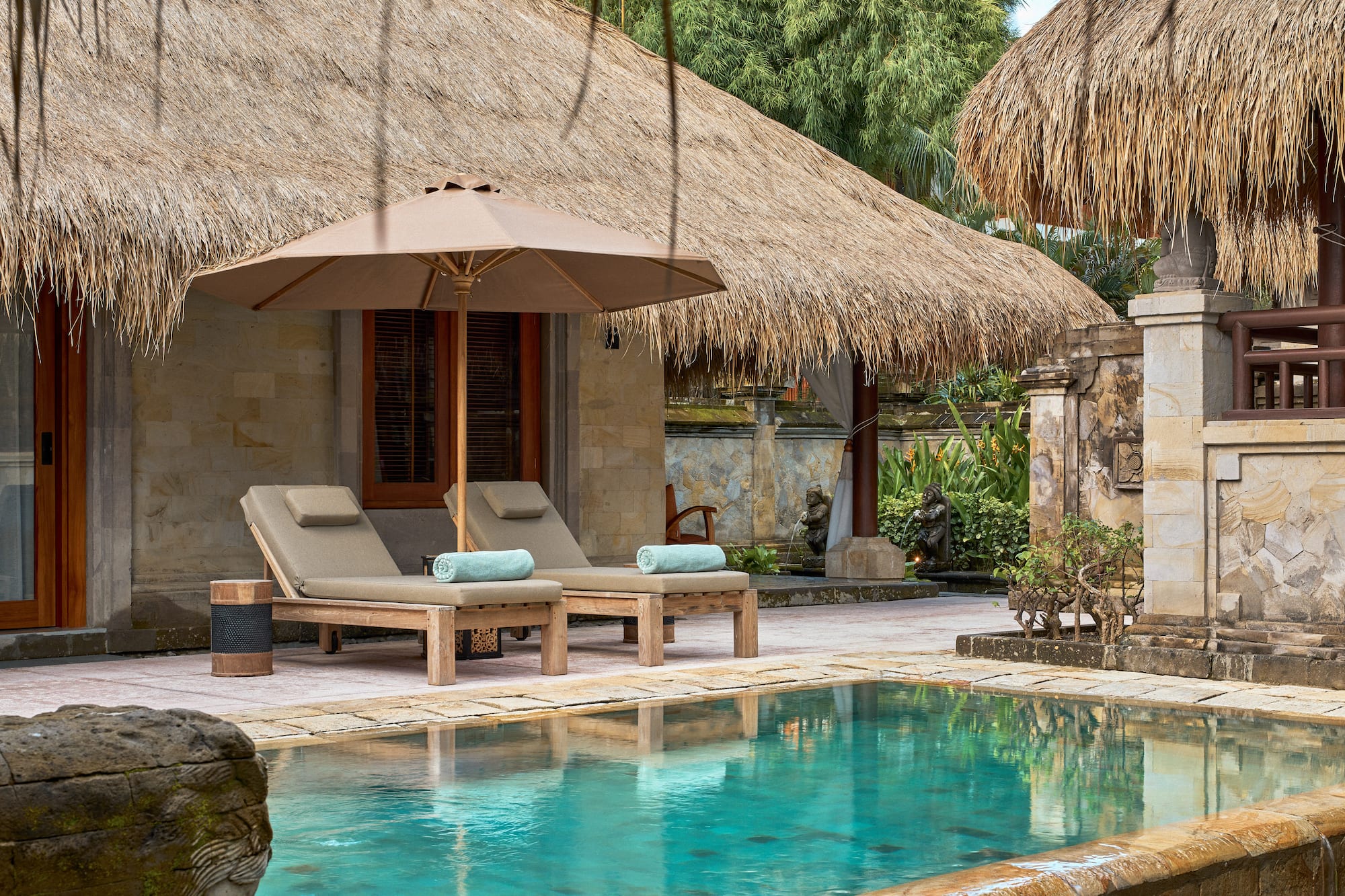 a pool with lounge chairs and umbrella by a building