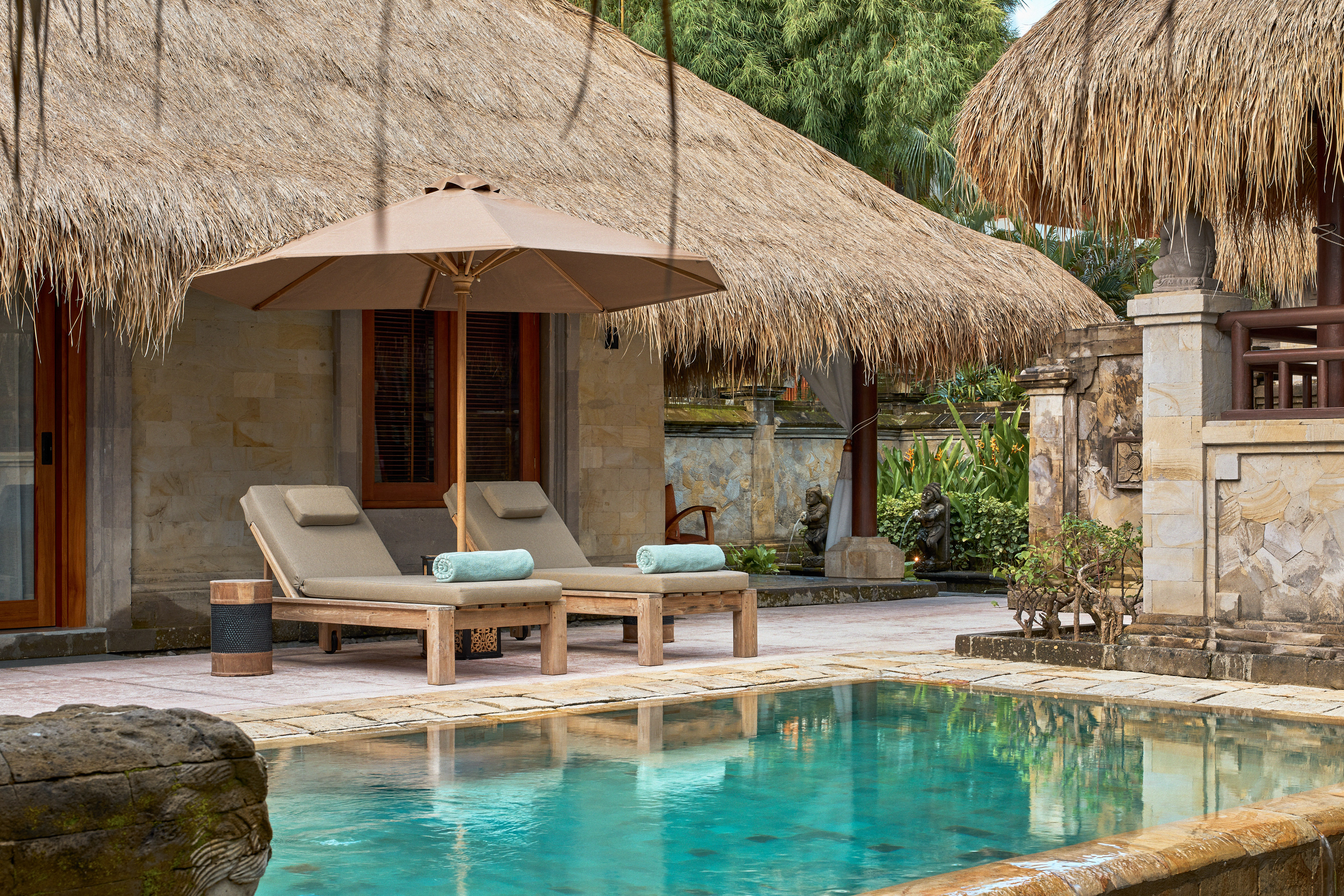 a pool with lounge chairs and umbrella by a building