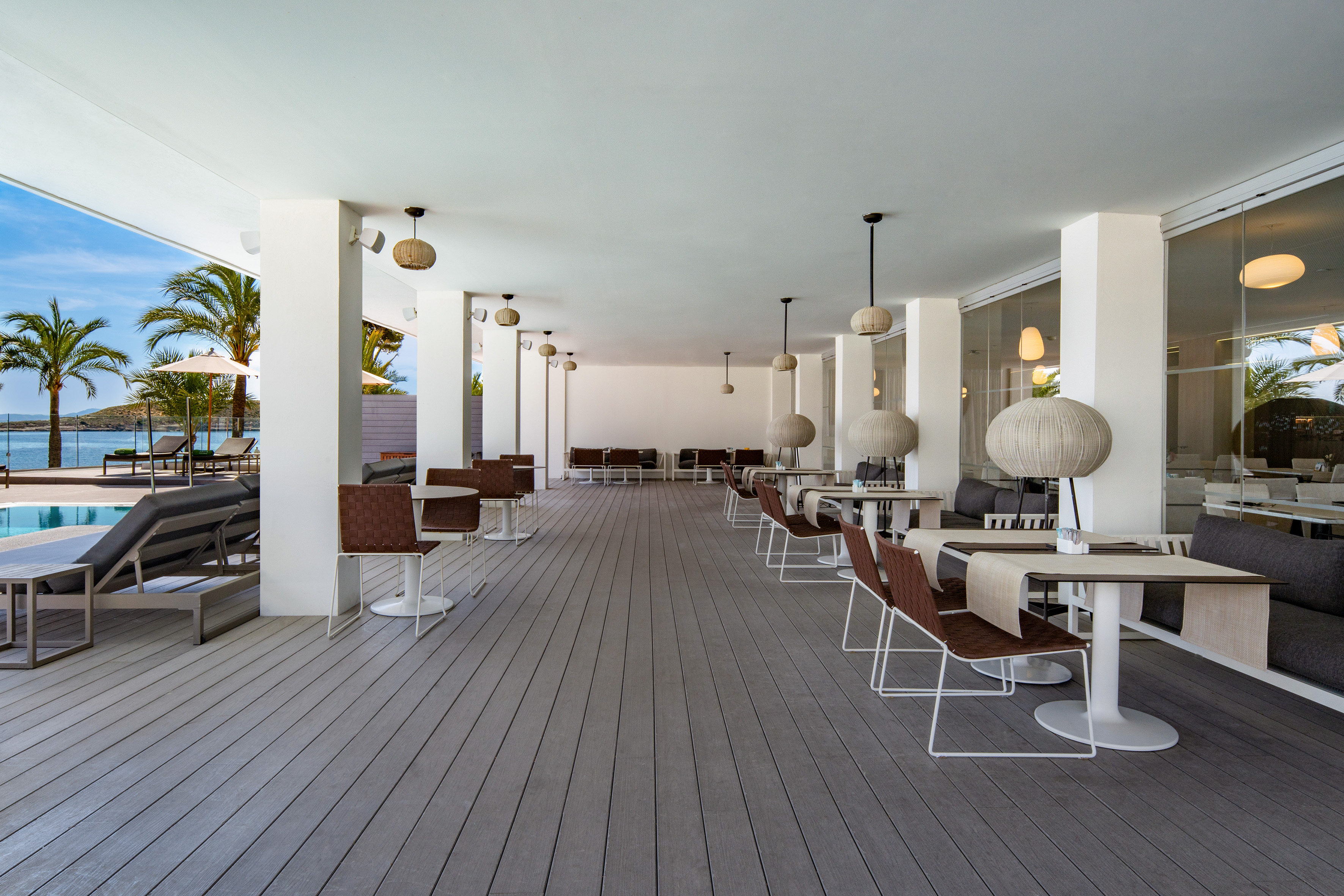 Elegant outdoor dining terrace by a pool, with ocean view and palm trees.
