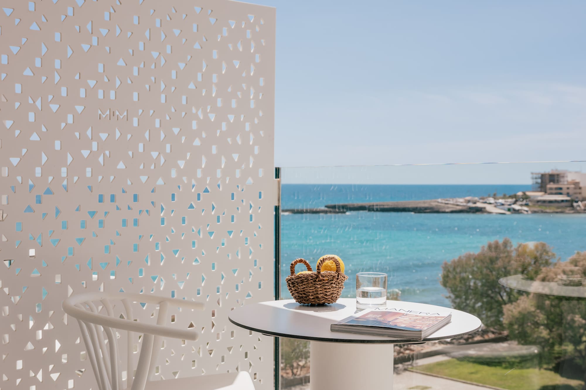 Balcón con vista al mar azul, mesa, silla y limones.