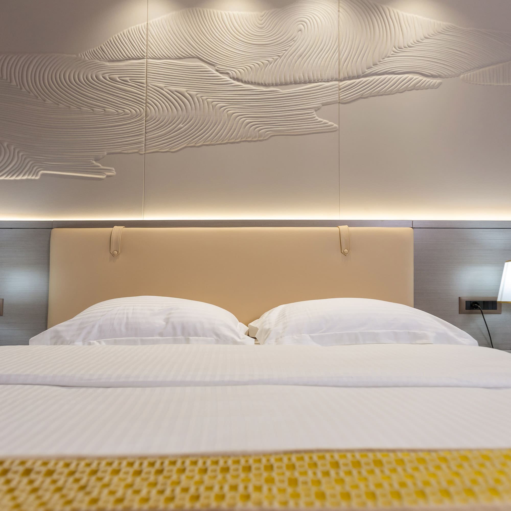 a bed with a lamp and a wall