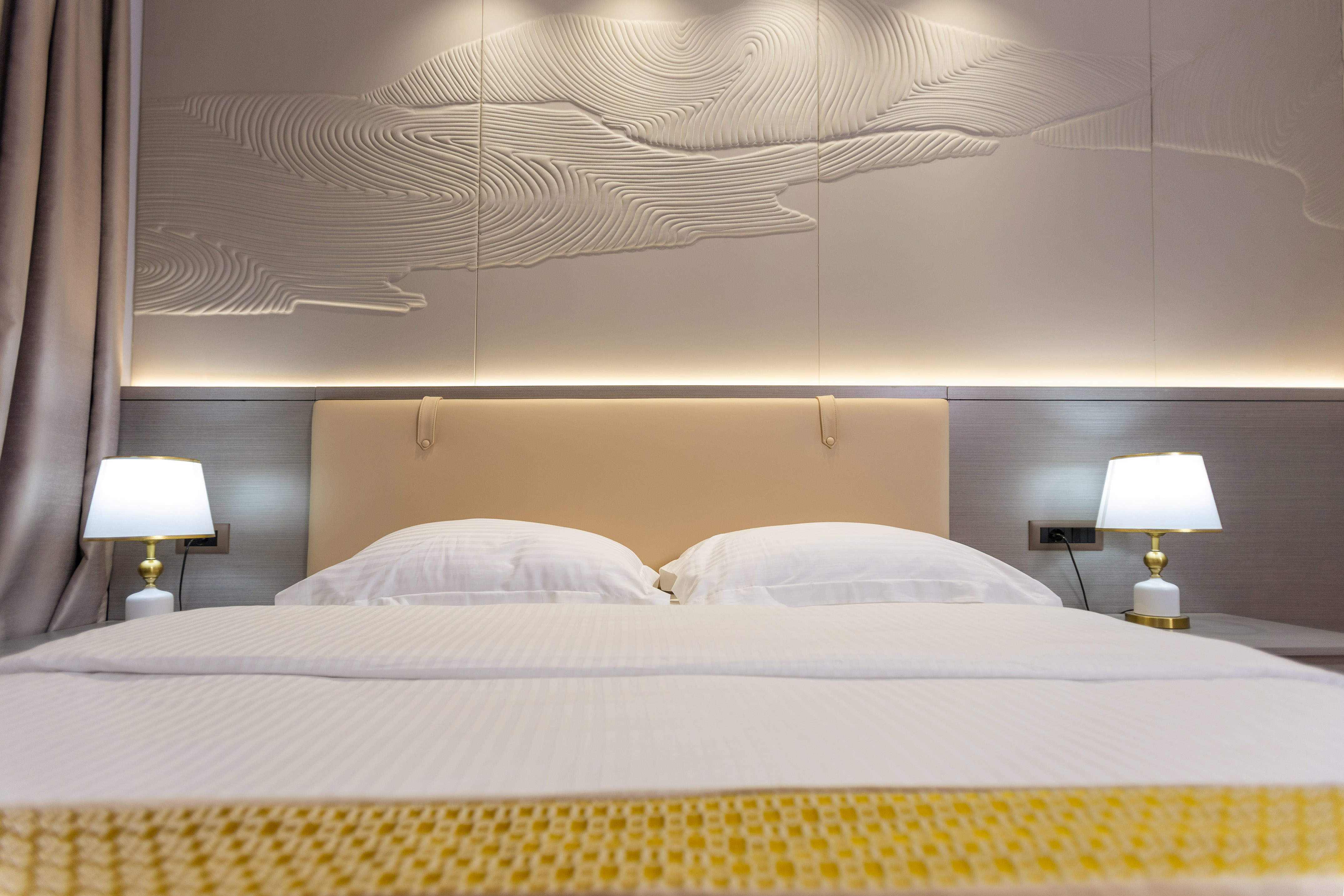 a bed with a lamp and a wall