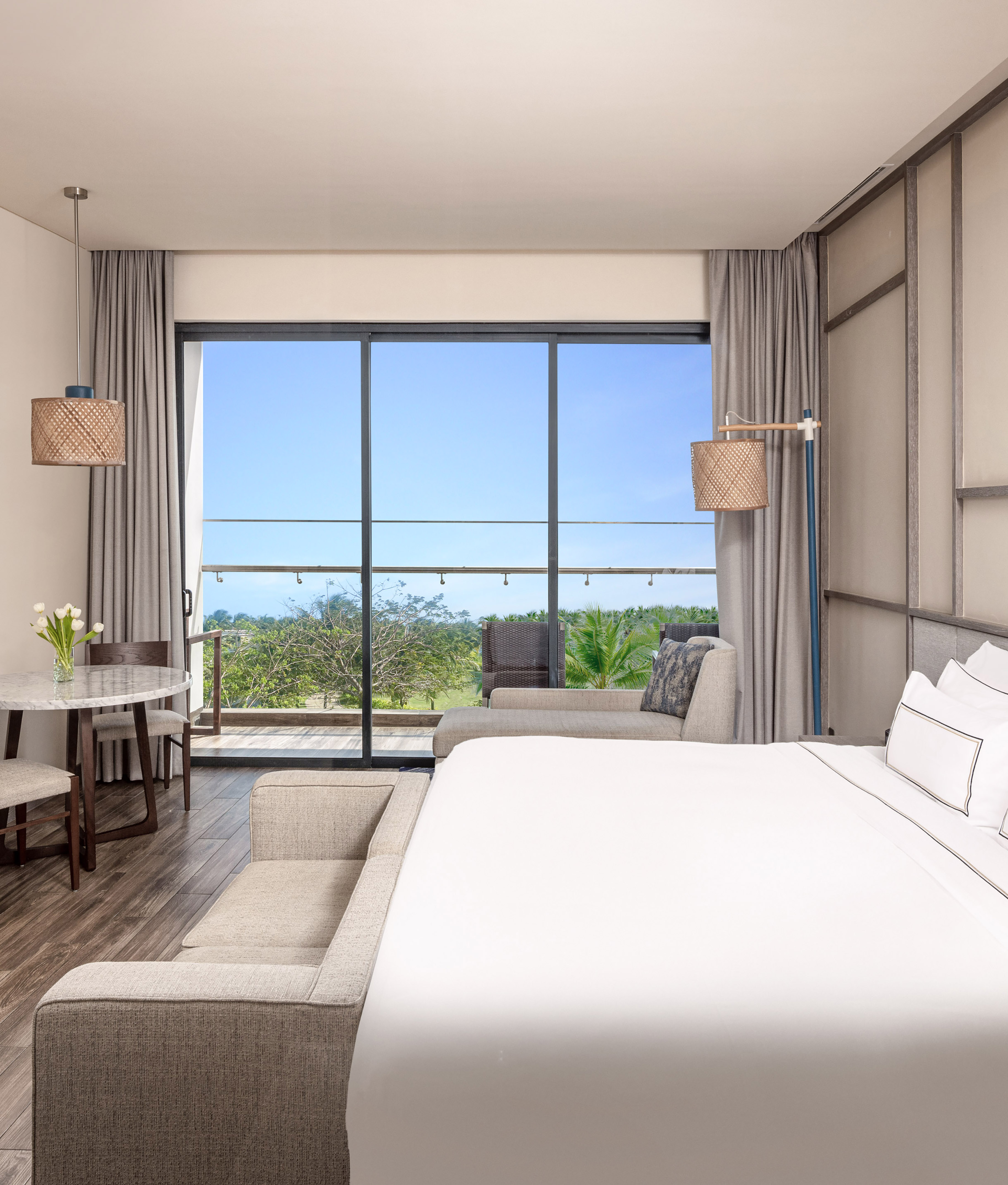 Luxury hotel suite with balcony, tropical resort view, and king bed.