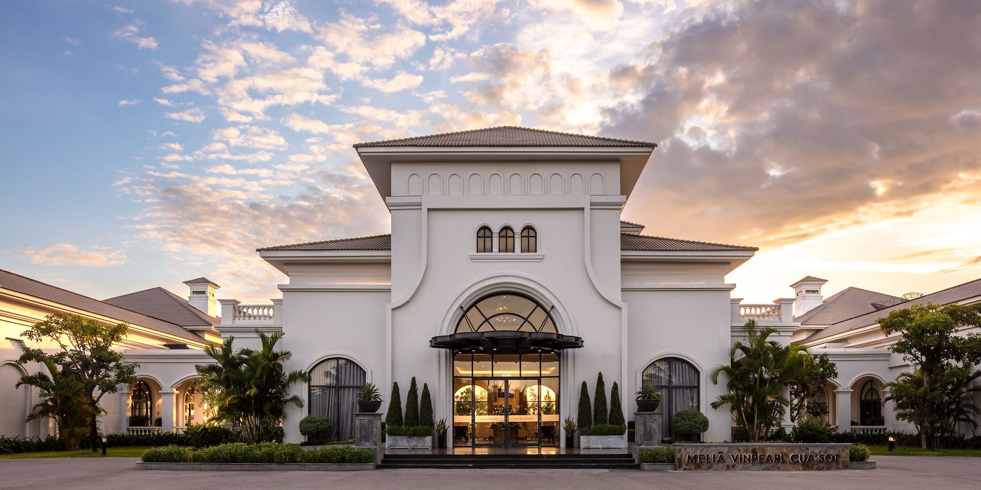 a building with a lot of trees and a cloudy sky