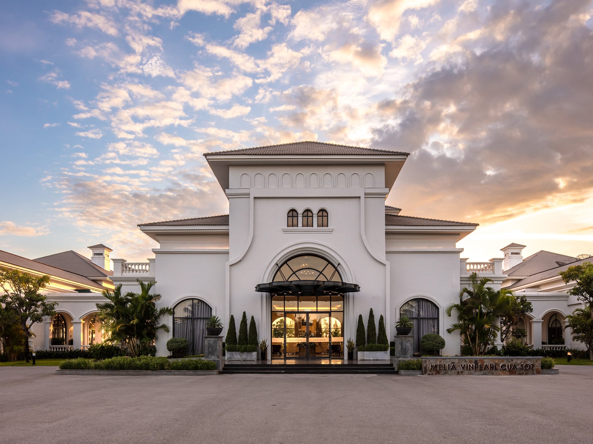 a building with a lot of trees and a cloudy sky